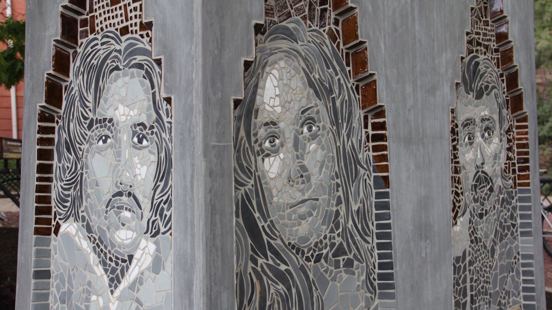 A concrete sculpture featuring the faces of three people. 