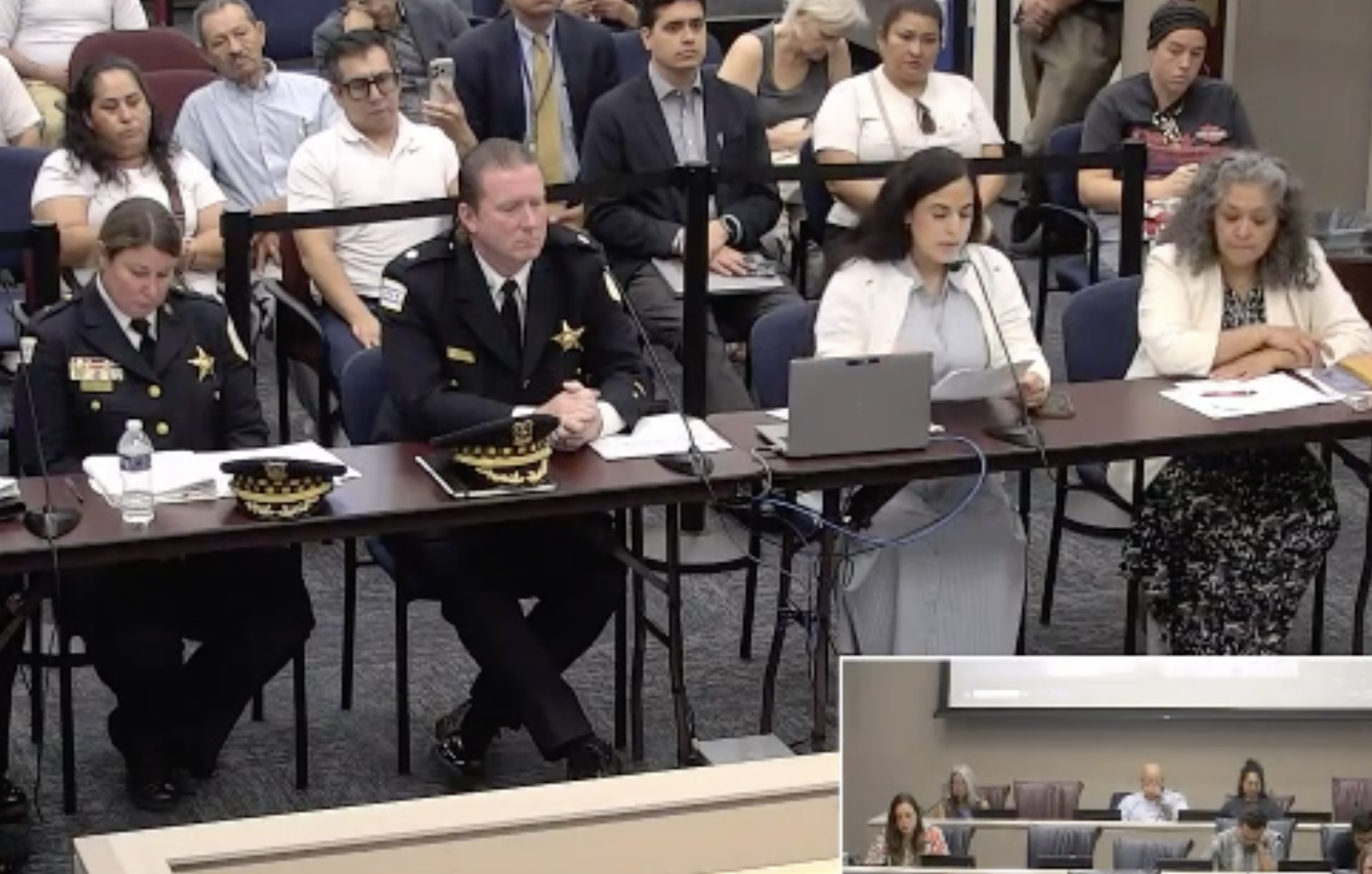 police and civilians sitting at a table 