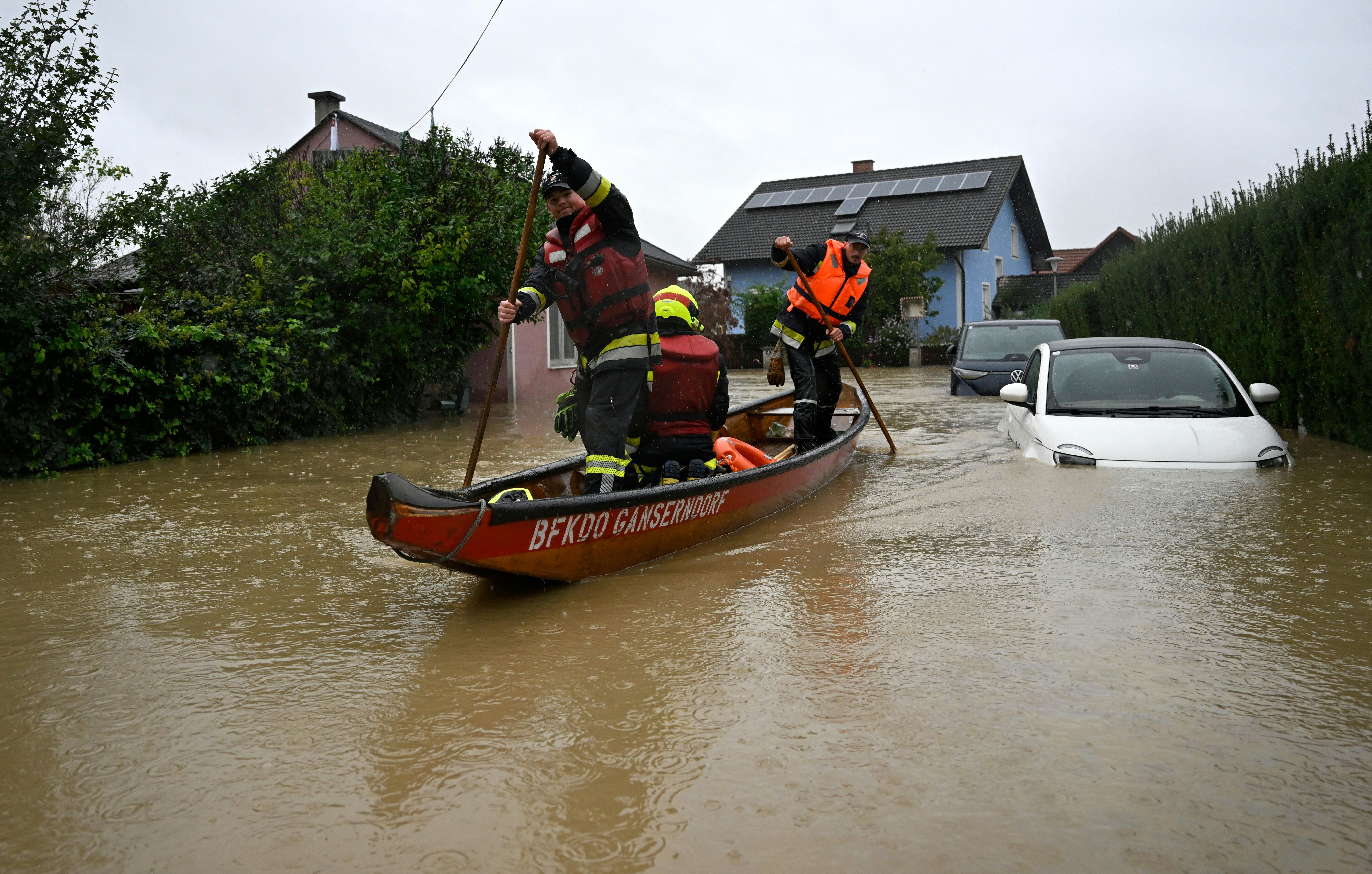 Firemen in a boat make their way past a car submerged by the floods in Rust im Tullnerfeld, Austria, on September 16