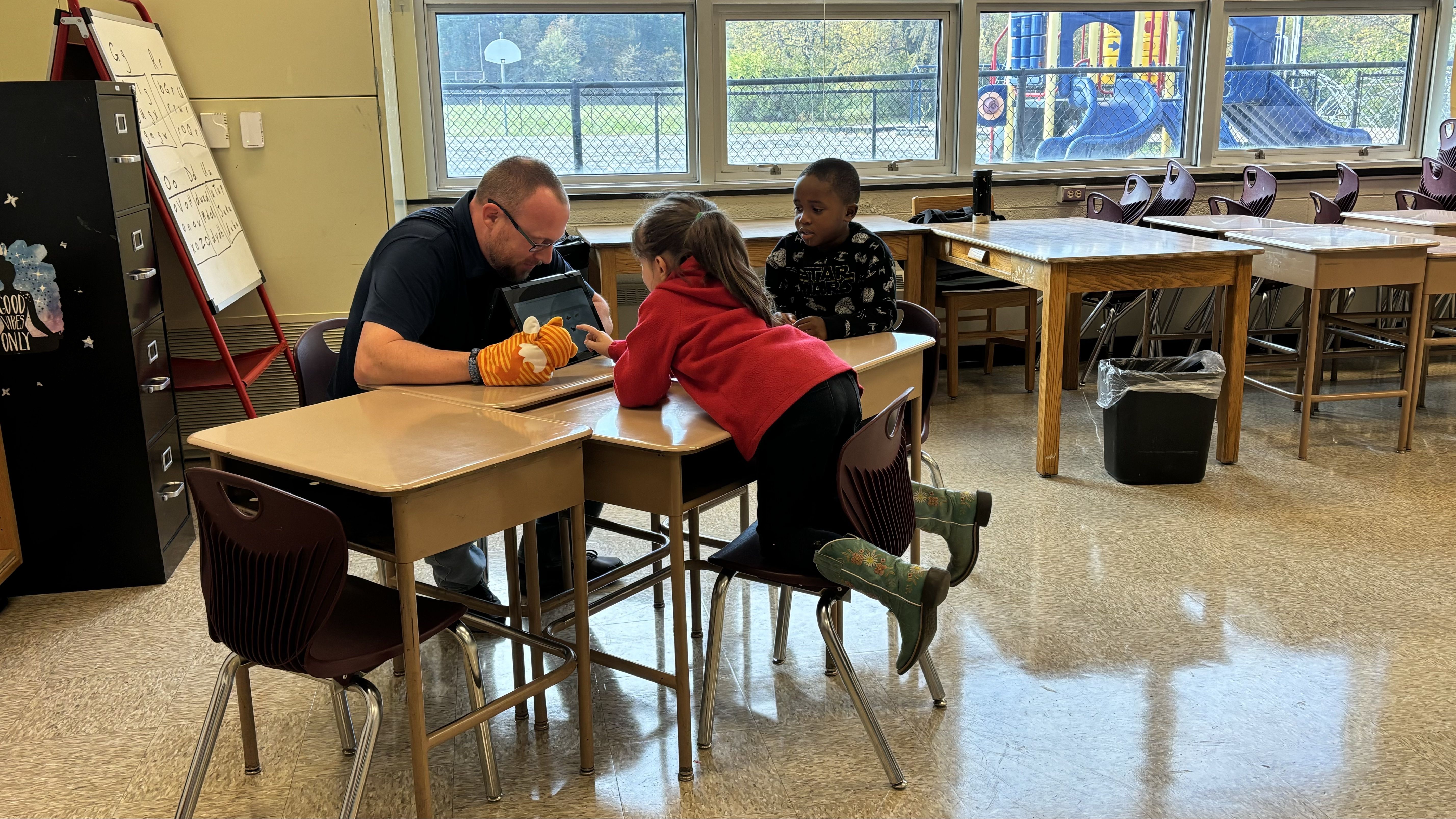 A man at a desk with two little kids.