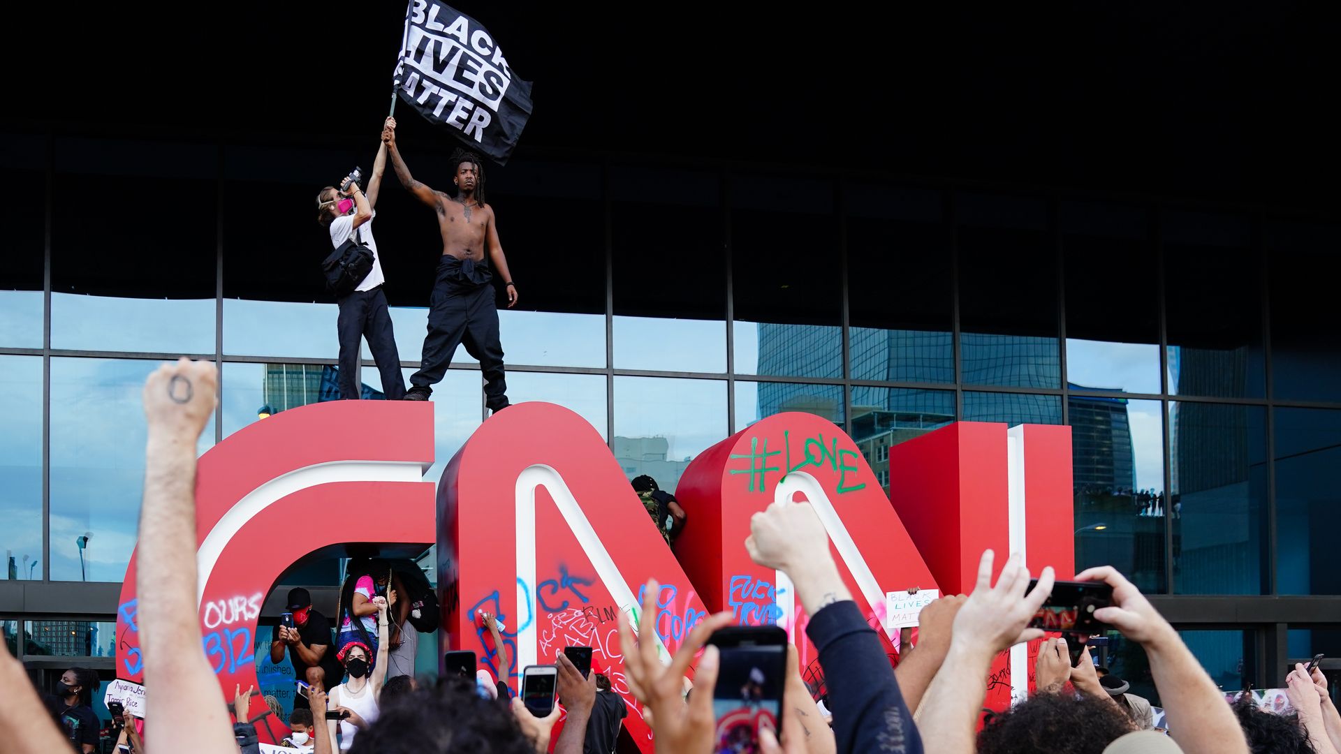 A man waves a Black Lives Matter flag atop the CNN logo during a protest in response to the police killing of George Floyd outside the CNN Center on May 29.