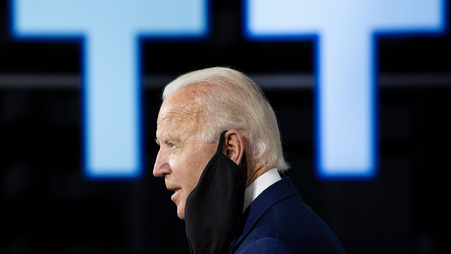 Joe Biden wears a mask hanging from one ear 