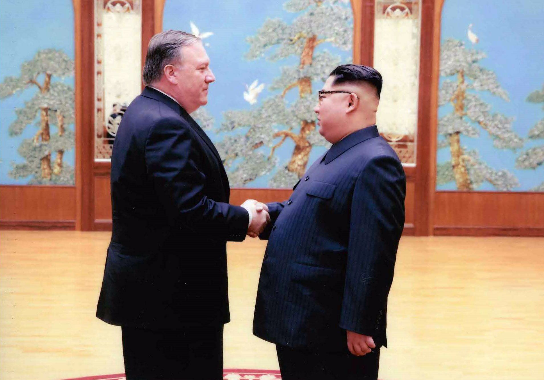 Mike Pompeo and Kim Jong-un shake hands.