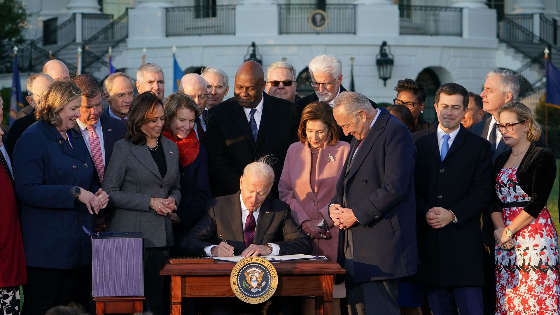 President Joe Biden surrounded by dignitaries as he signs a historic infrastructure law.