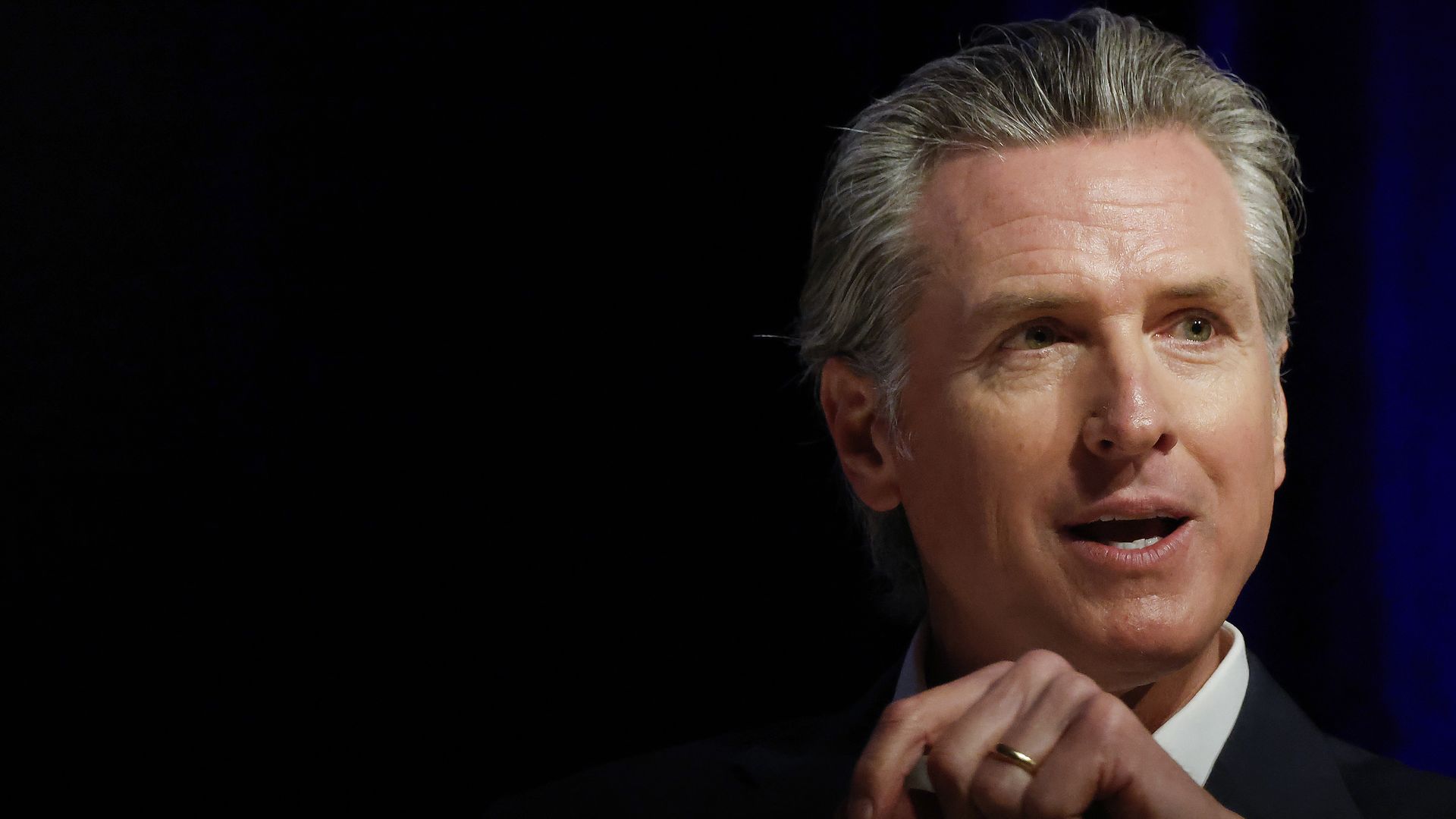 California Gov. Gavin Newsom speaks against a dark backdrop.