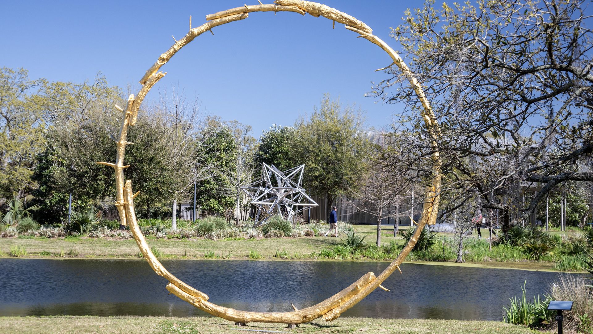 Image shows a gold circle sculpture in the sculpture garden in New Orleans.