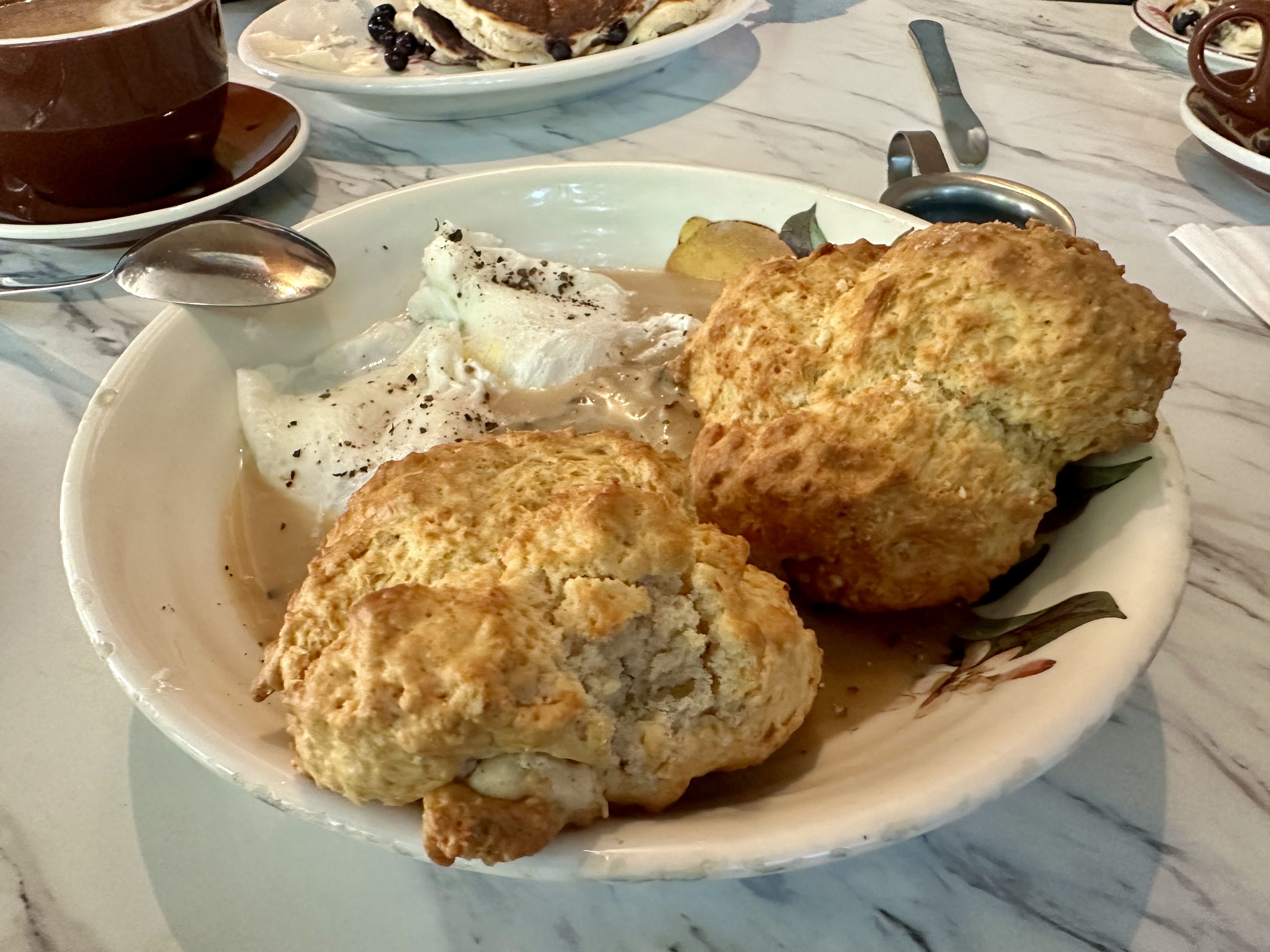 A plate with biscuits and gravy and poached eggs.