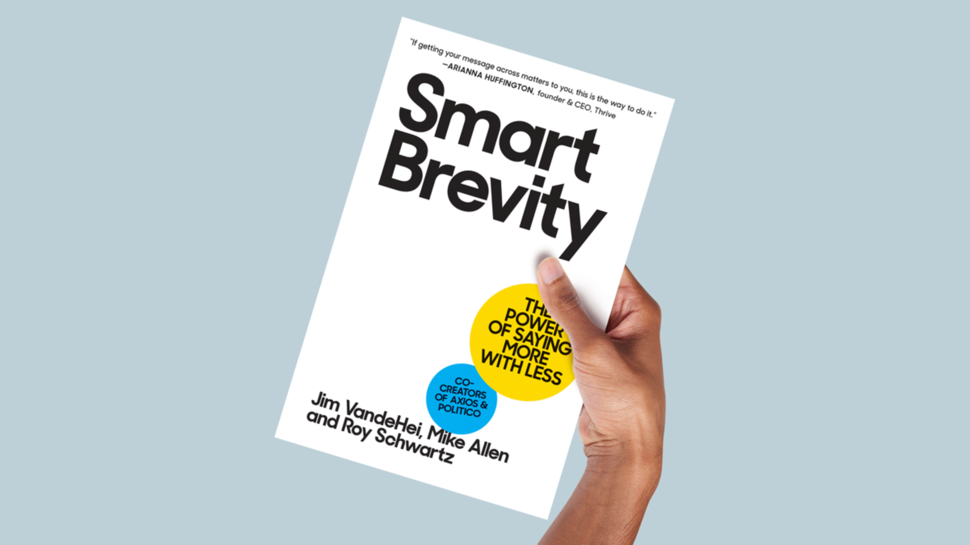 A hand holding a white book that reads "Smart Brevity."