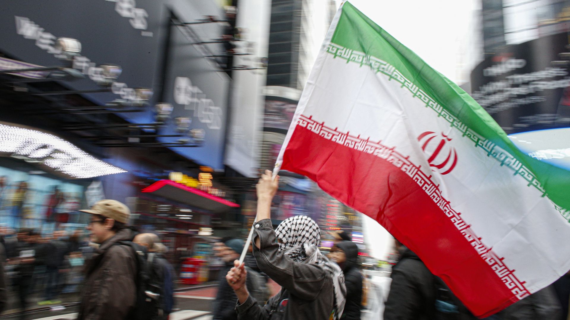 In this image, a person holds the Iranian flag