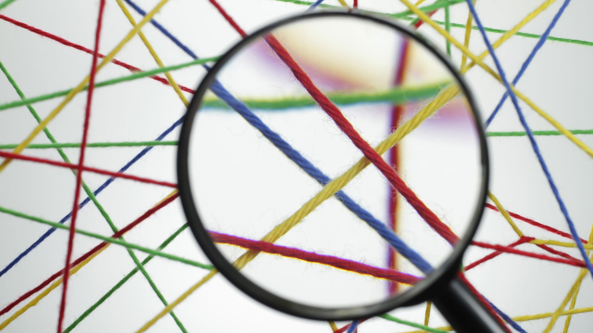 Close-Up Of Magnifying Glass Against Colorful Threads
