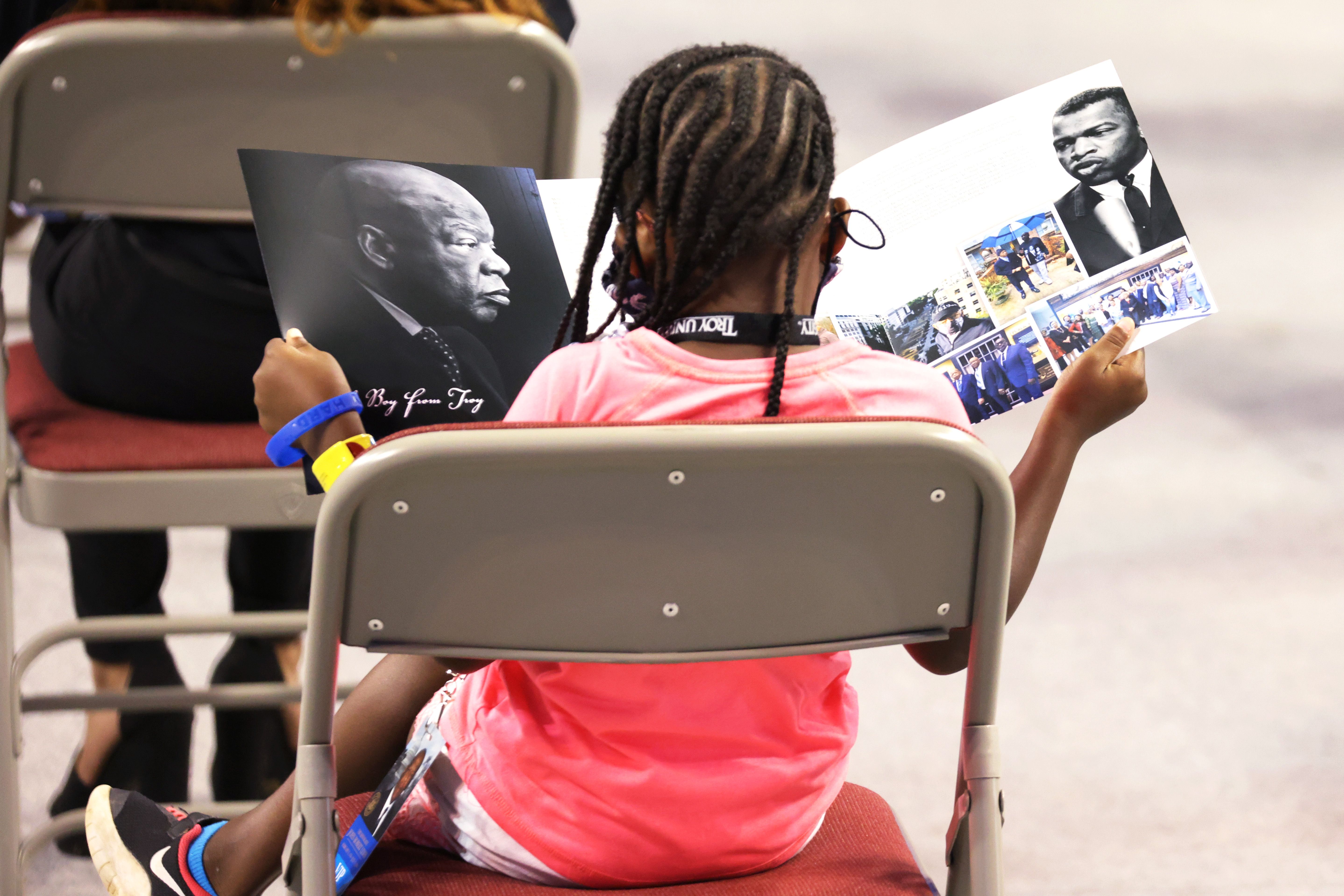 A young girl reads a program during “​The Boy from Troy”​ service celebrating the life of Former US Rep. John Lewis (D-GA) o​n July 25, 2020