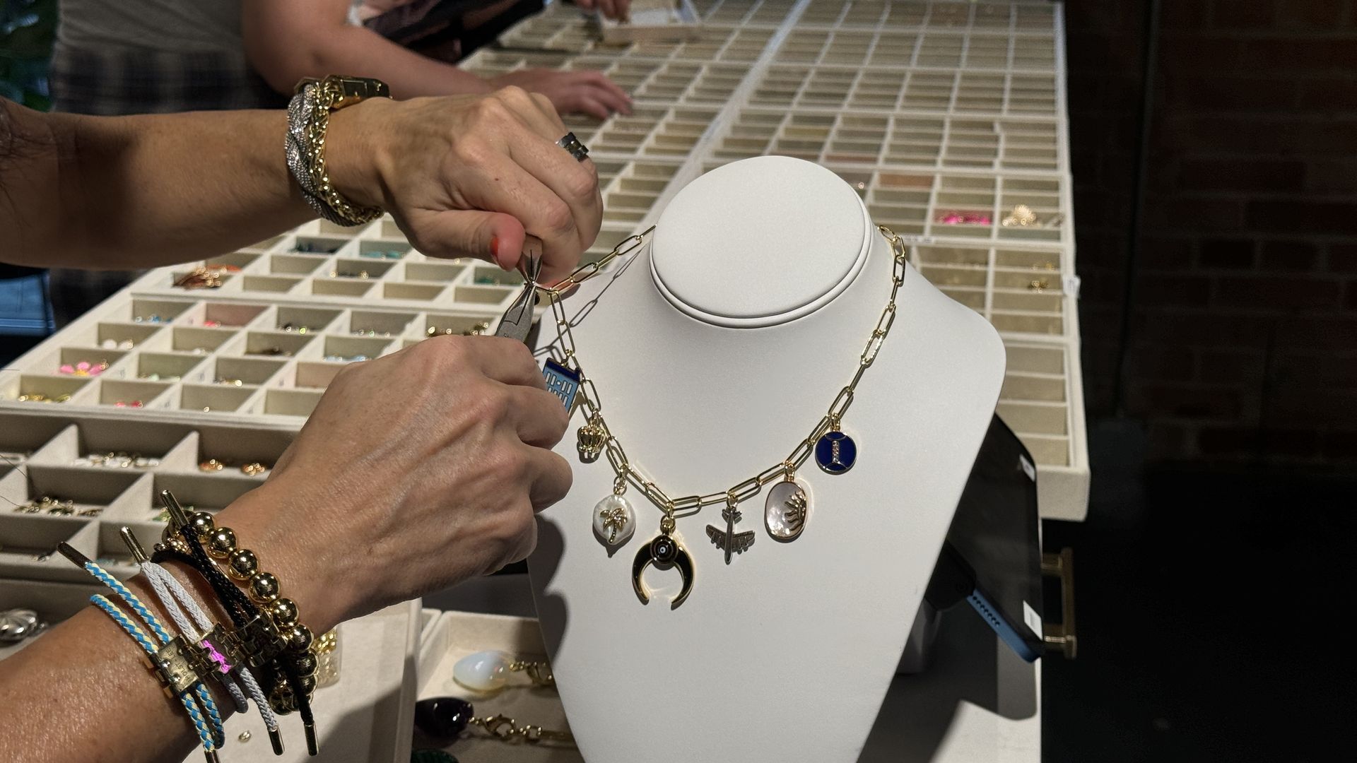 two hands fastening a charm onto a necklace