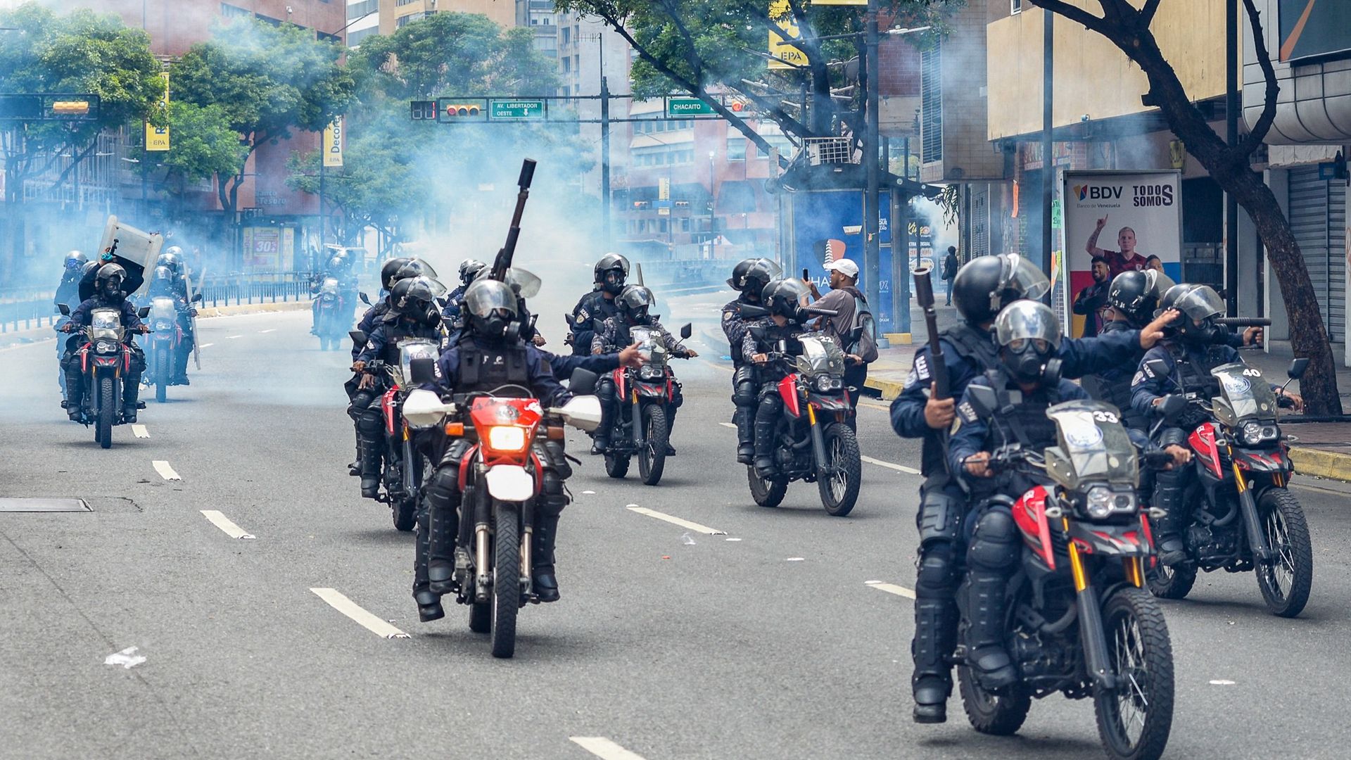 Members of the National Guard riot squad ride away from teargas at Chacao neighbourhood as opponents of Venezuelan President Nicolas Maduro take part in a demonstration, in Caracas on July 30, 2024. Security forces fired tear gas and rubber bullets at protesters and an NGO said 11 people have been k
