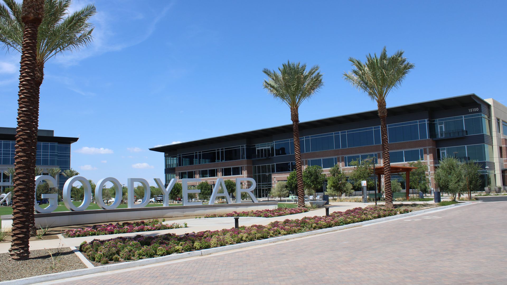 A three-story office building behind a metal sign that reads Goodyear