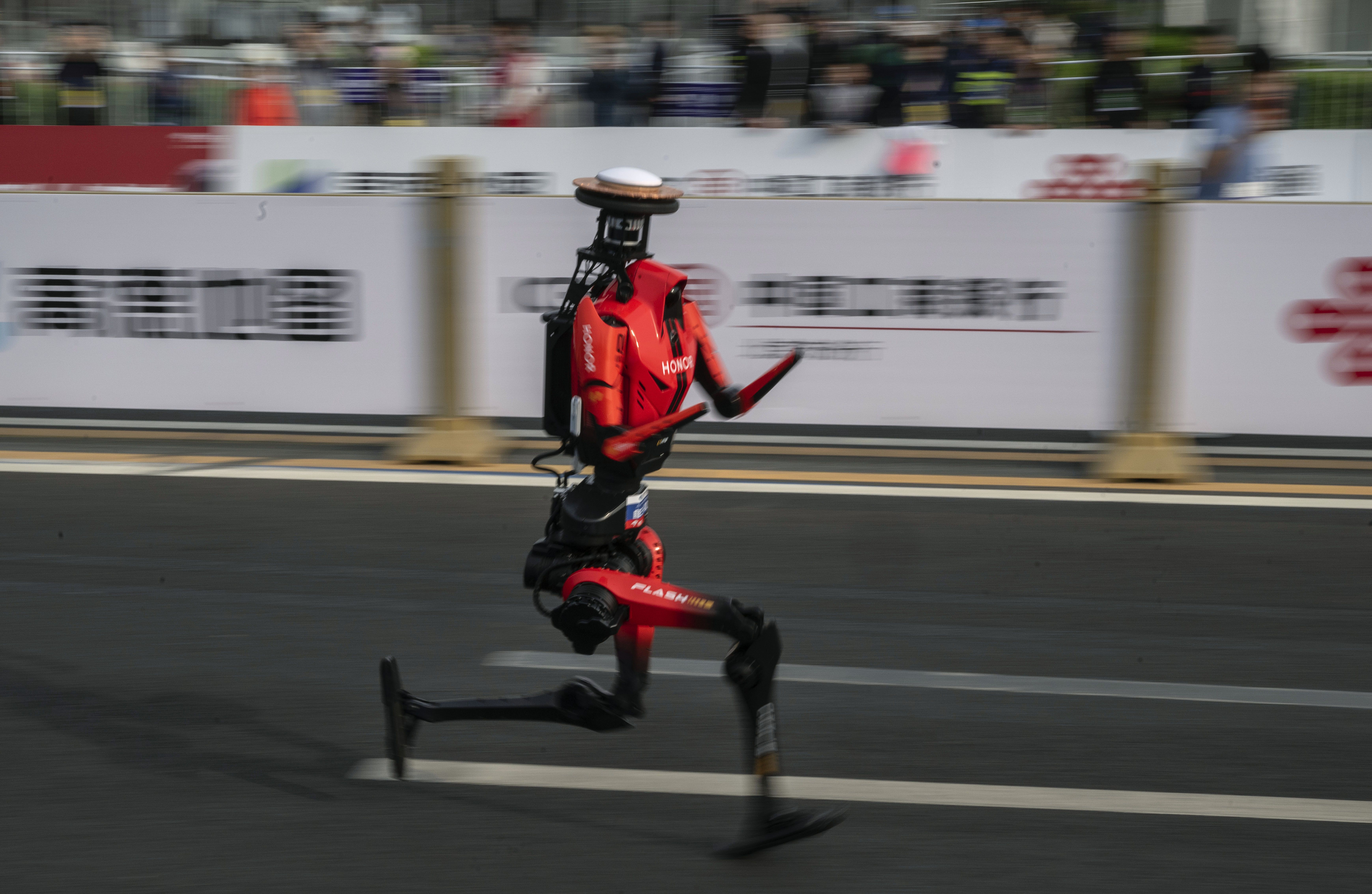 BEIJING, CHINA - APRIL 19: The fastest humanoid robot, an H1made by Honor, runs beside human runners at the start on its way to winning the Beijing Humanoid Half Marathon on April 19, 2026 in Beijing, China. The robot finished with a net time of 50 minutes and 26 seconds. More than 100 humanoid robo