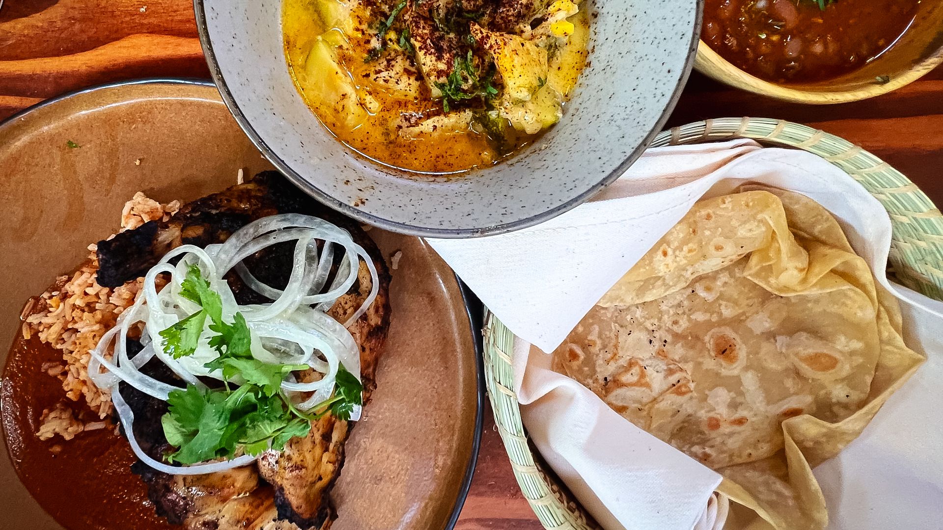 A spread of four dishes with chicken, squash, beans and tortillas. 