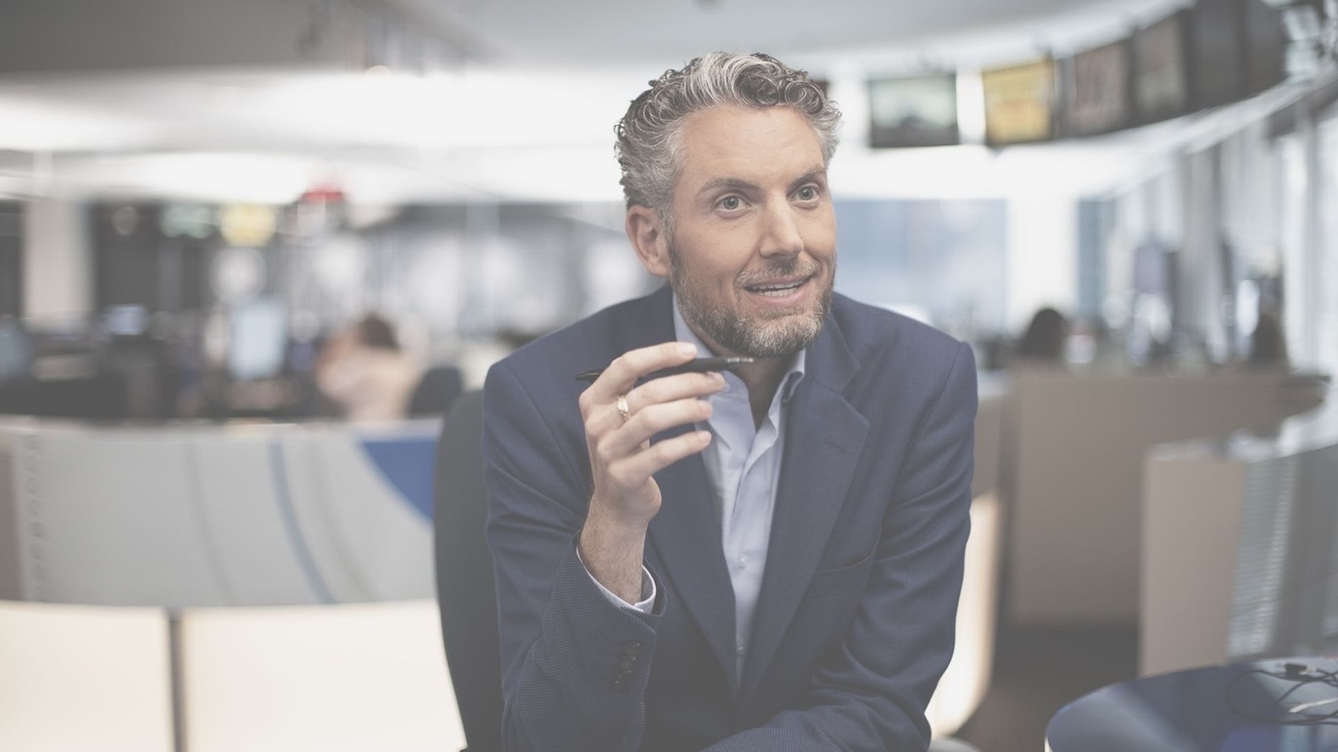 Photo of a man holding a pencil talking to a camera