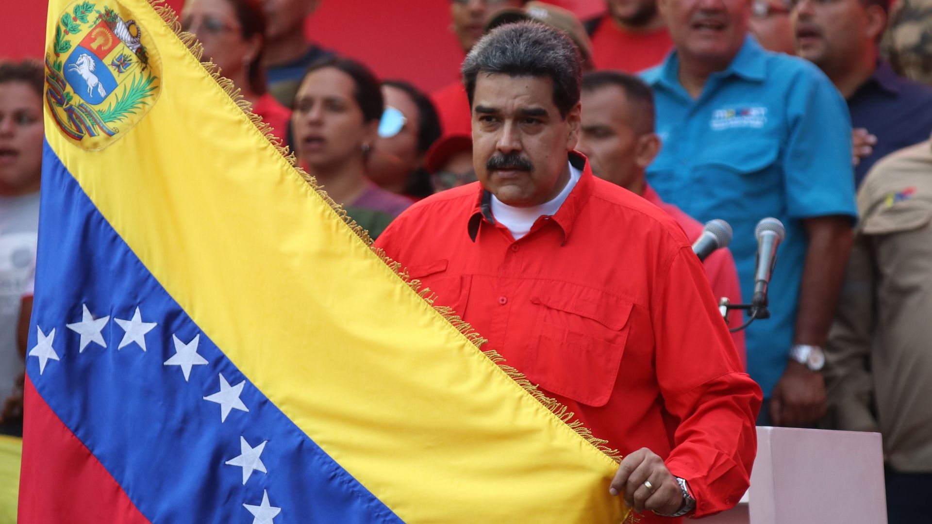 Nicolas Maduro holding up the Venzuelan flag at a rally