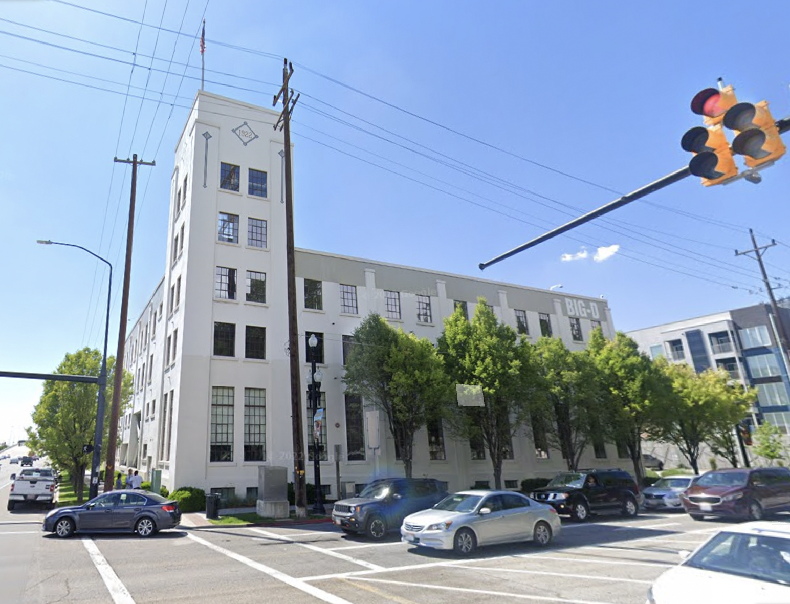 A white industrial building with a tower of small, window rooms, on a city street corner.