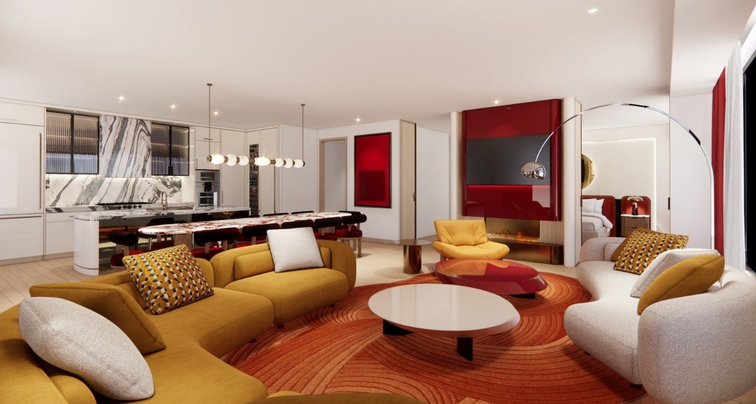 A modern open-plan living area with mustard-yellow sofas around a white round coffee table on an orange circular rug, a red wall, curved arch to a bedroom, and a marble backsplash kitchen in the background.
