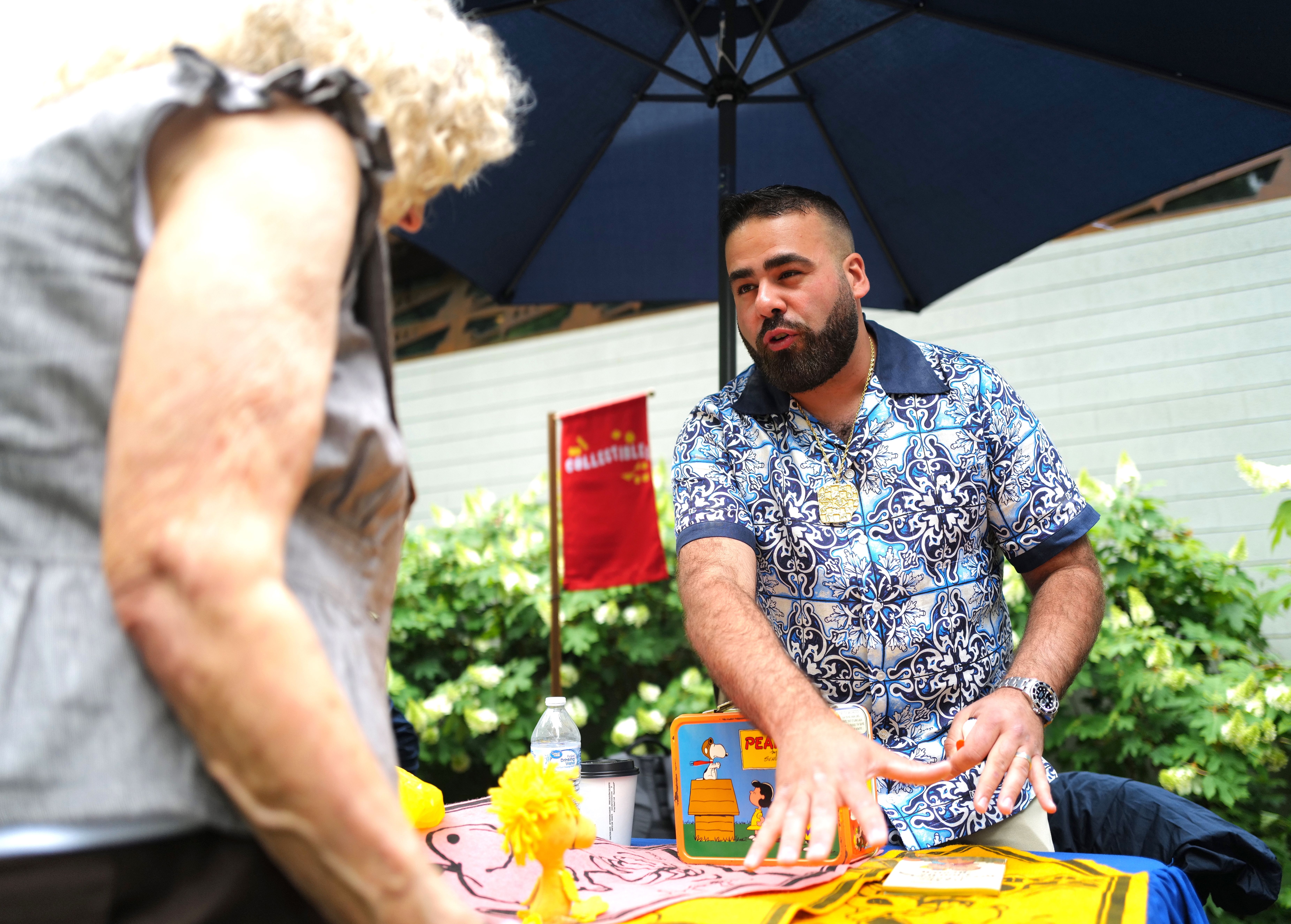 A man in a print shirt appraises Peanuts memorabilia. 