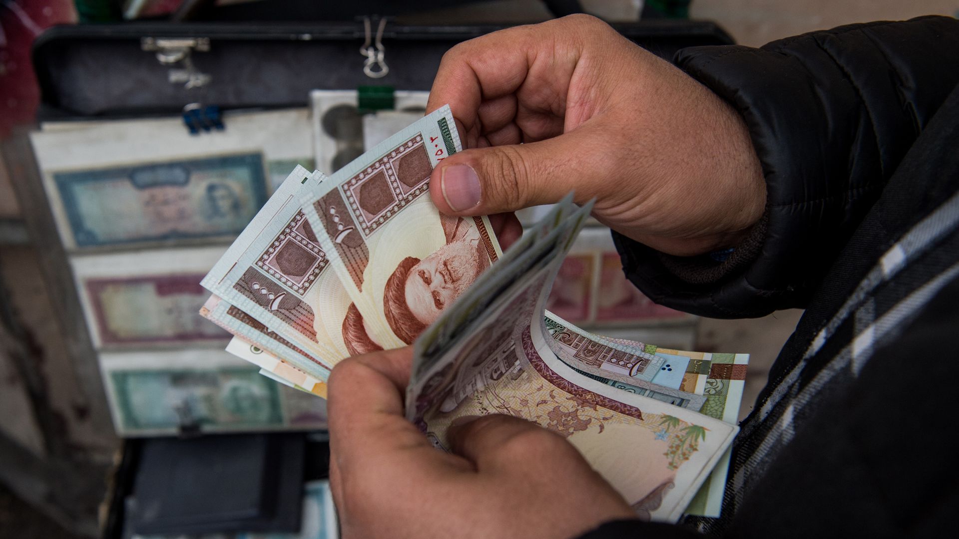 A currency trader counts Iranian rial banknotes 