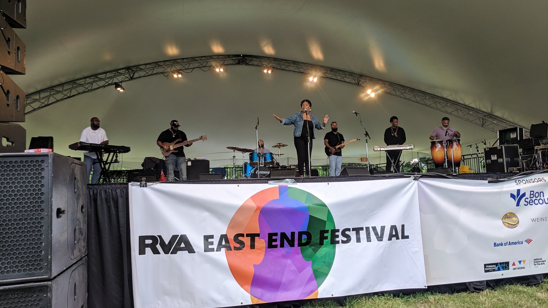 musicians on a stage under a big white tent