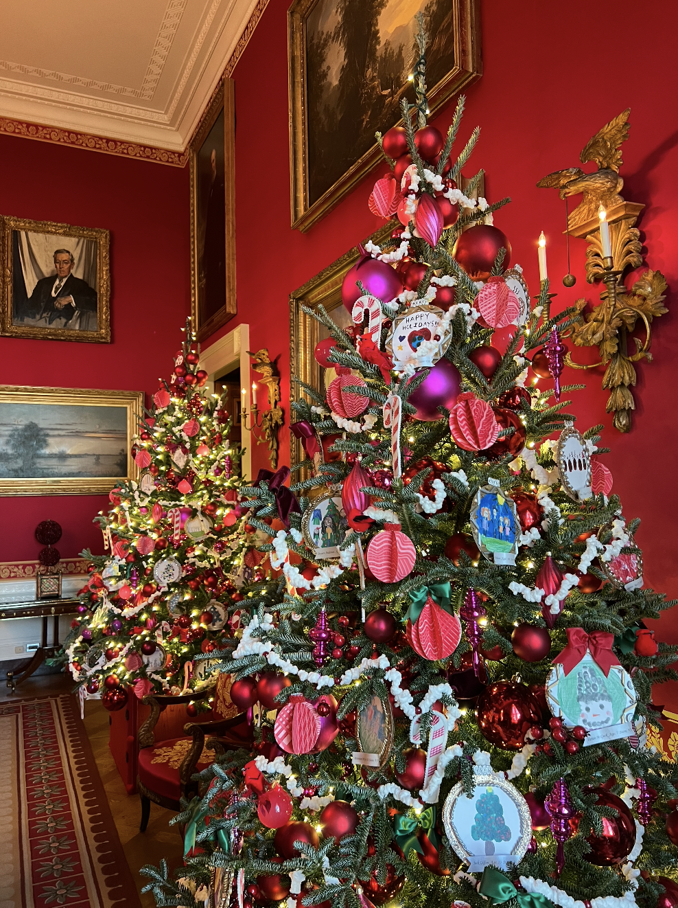 The Red Room at the White House with two Christmas trees decorated with lots of lights and ornaments. 