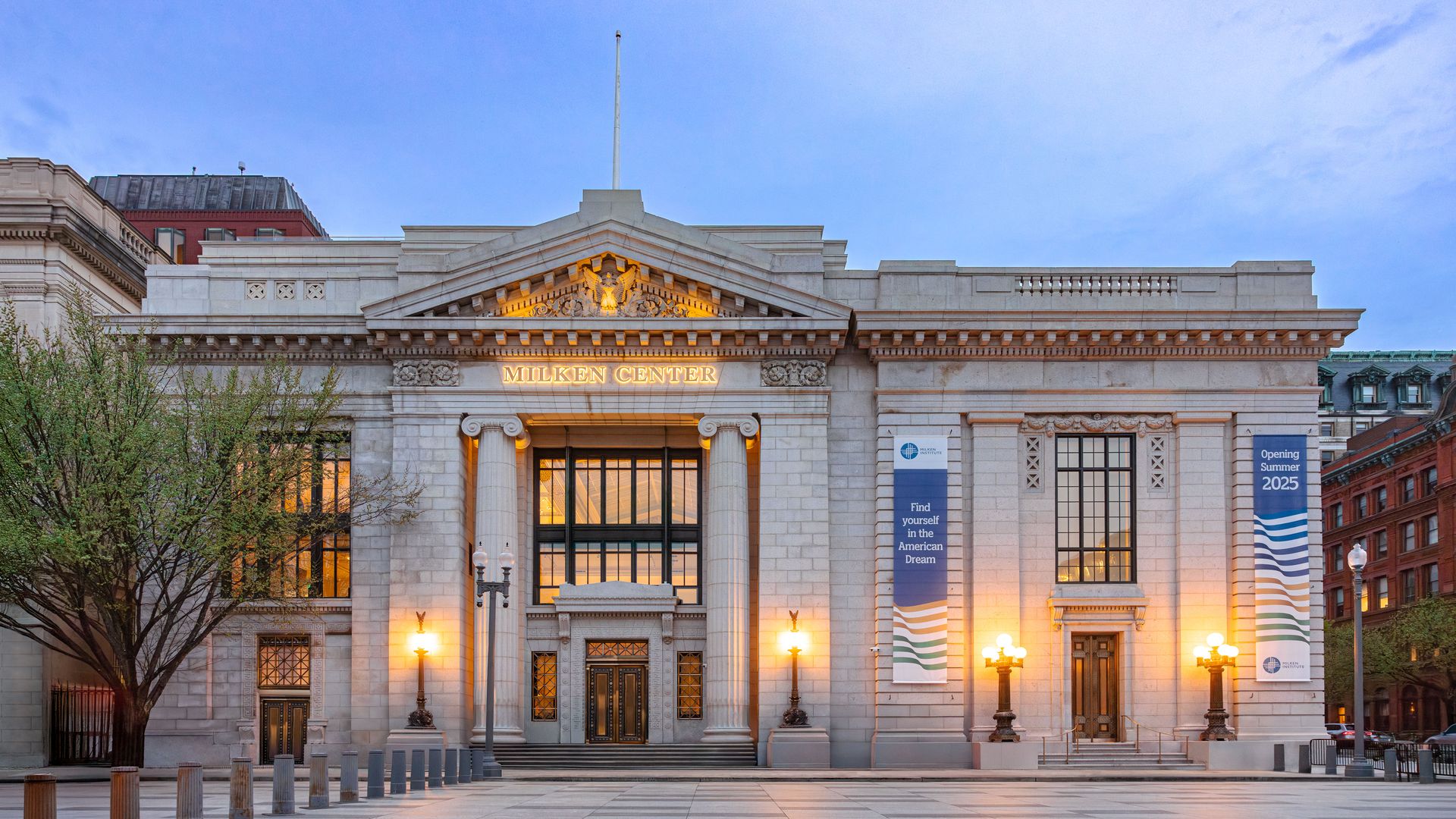 The grand Milken Center building at dusk with illuminated lamps, tall columns, and banners reading "Find yourself in the American Dream" and "Opening Summer 2025" against a twilight sky.
