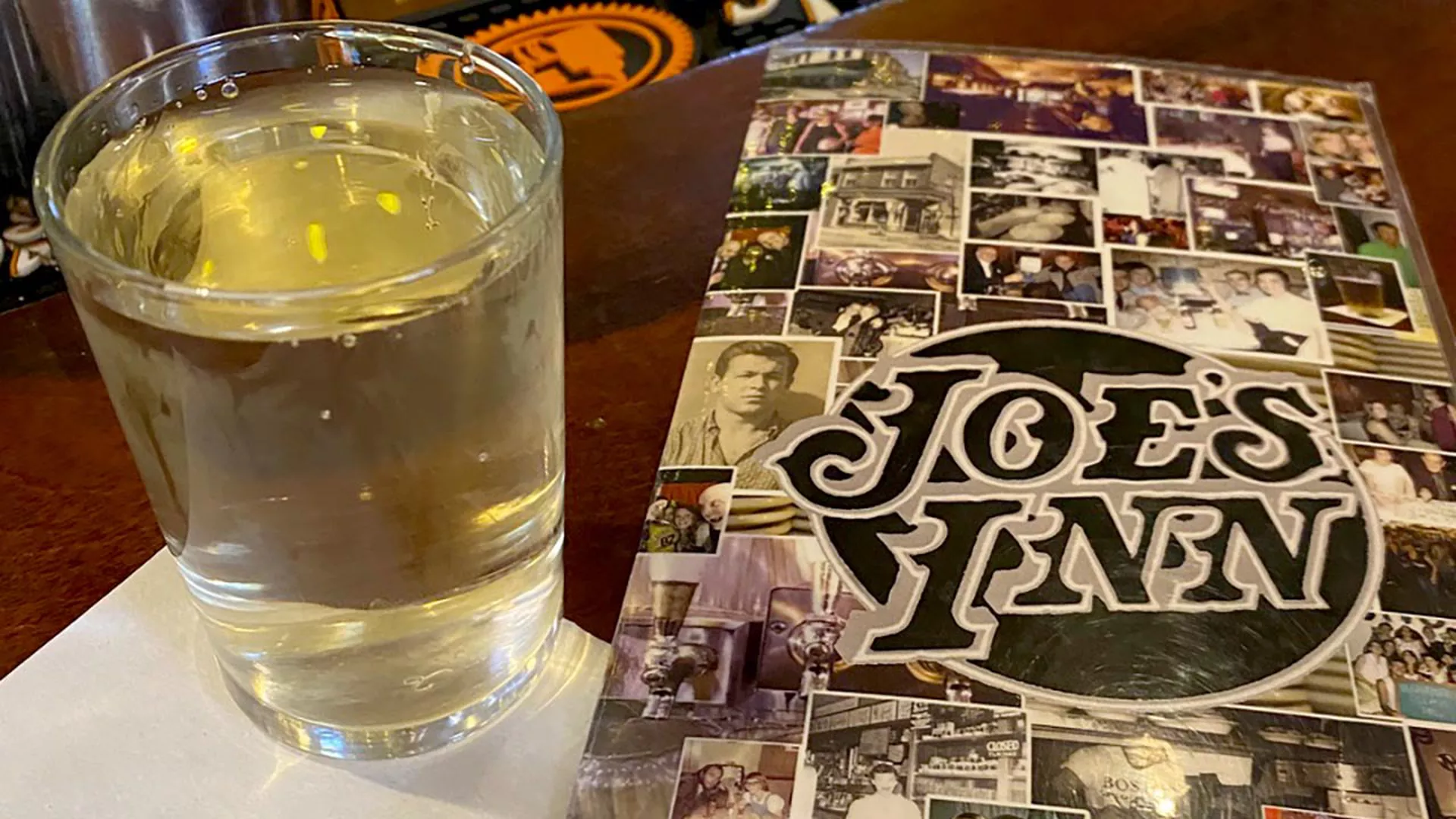 A glass of wine next to a Joe's Inn menu