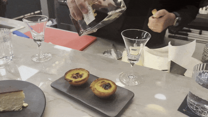 A man pours a bottle of liqueur into a dessert wine glass.