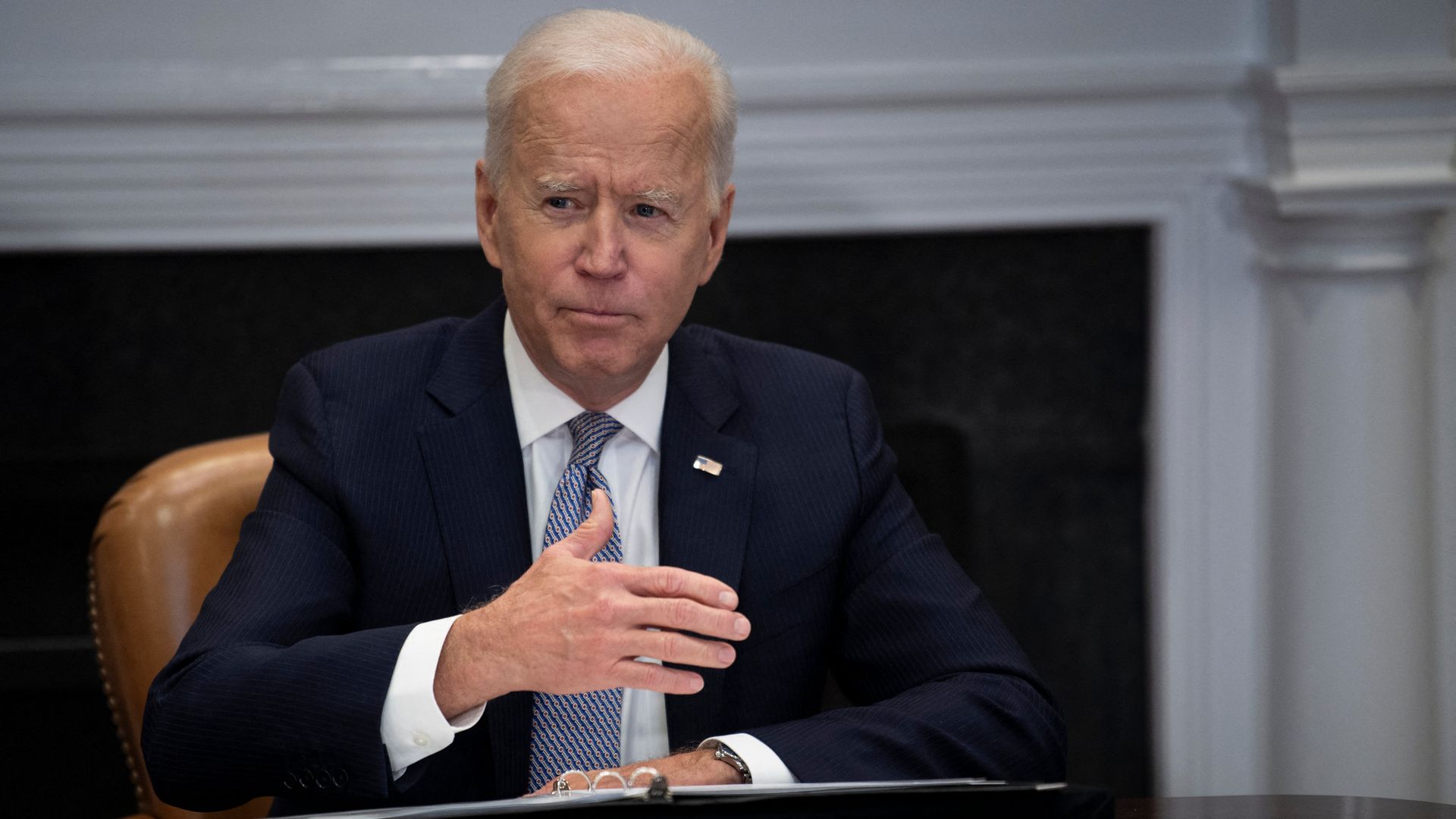 Joe Biden sits behind a desk 