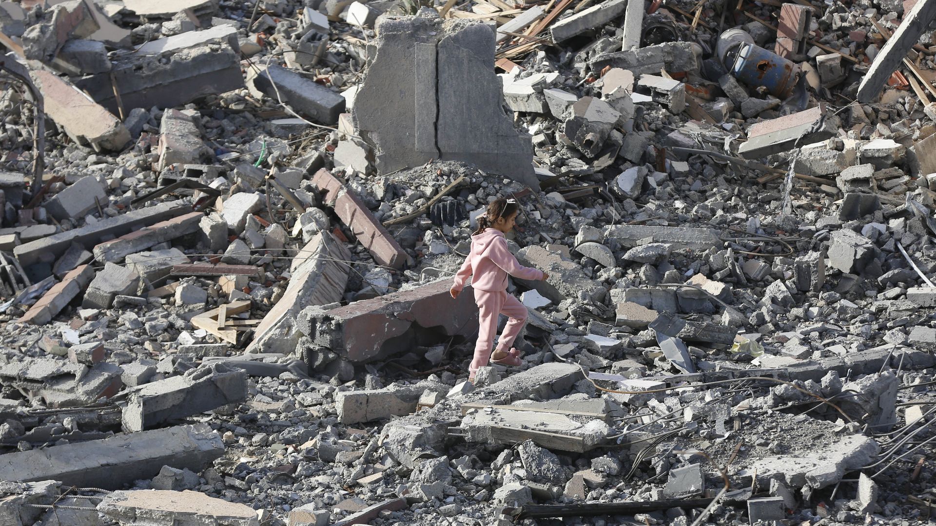girl walks among rubble in Gaza
