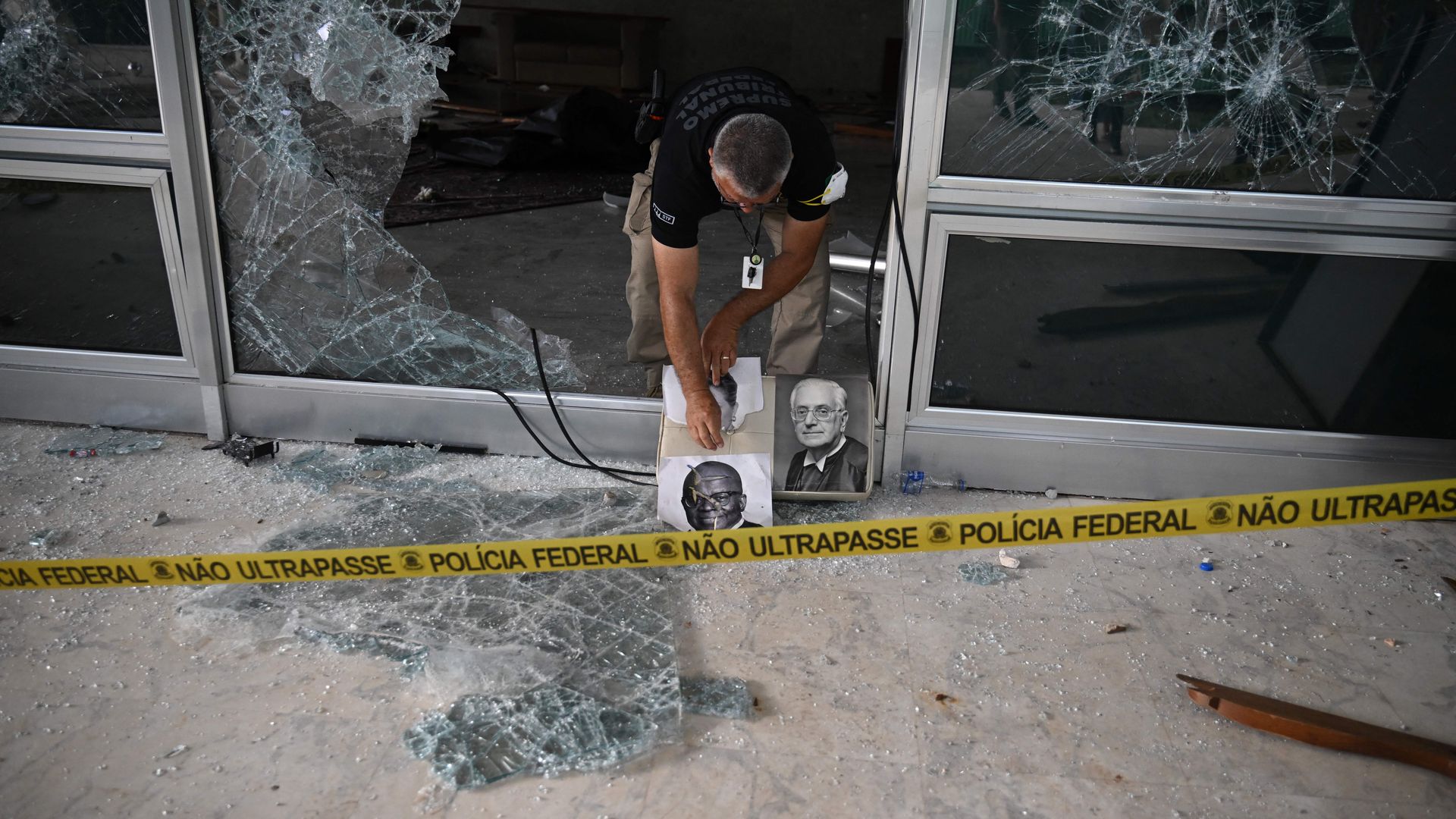 a police officer leans through broken glass in Brasilia, Brazil 