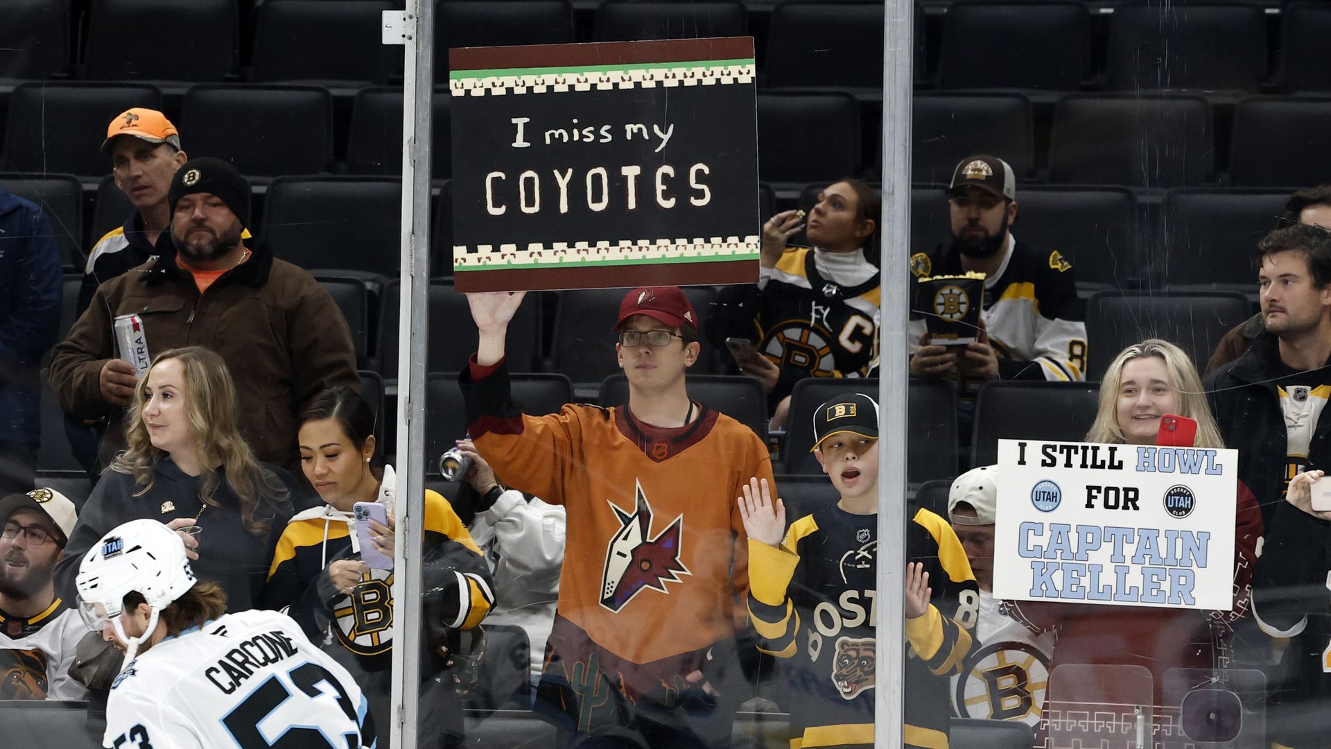 A man holding a sign that says, "I miss my coyotes" at a hockey game. 