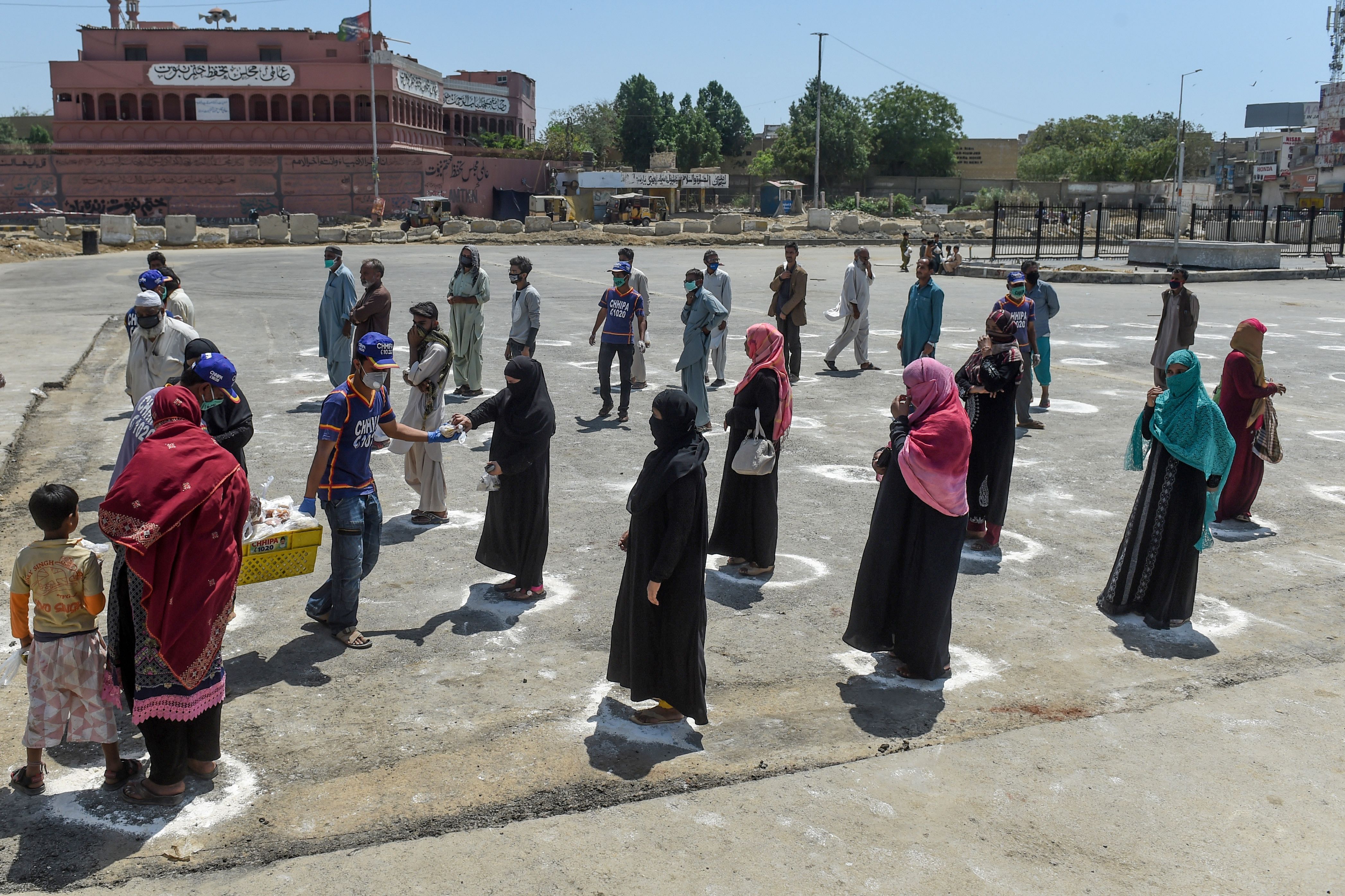 People stand in designated areas marked on the ground to maintain social distanciation  in Karachi on March 27