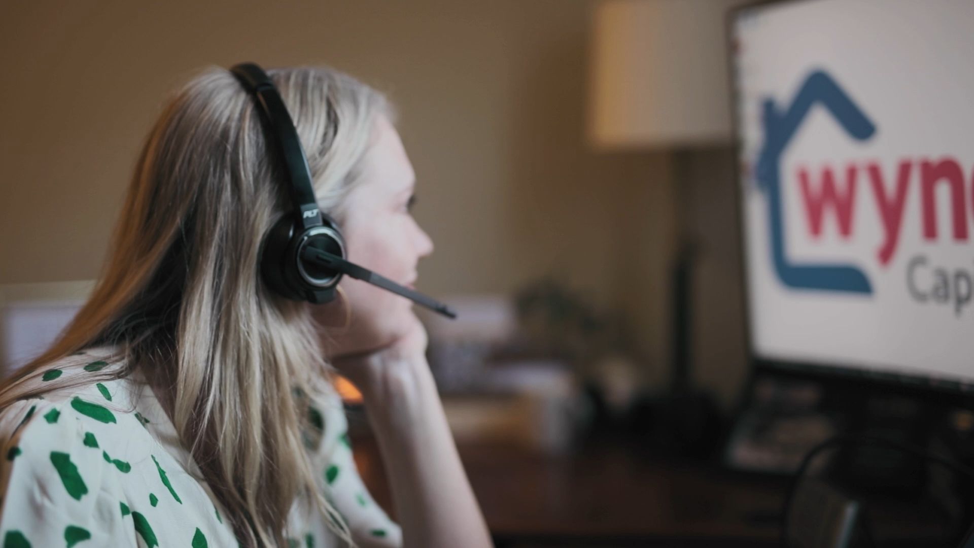 A woman with a headset on looks at a computer screen