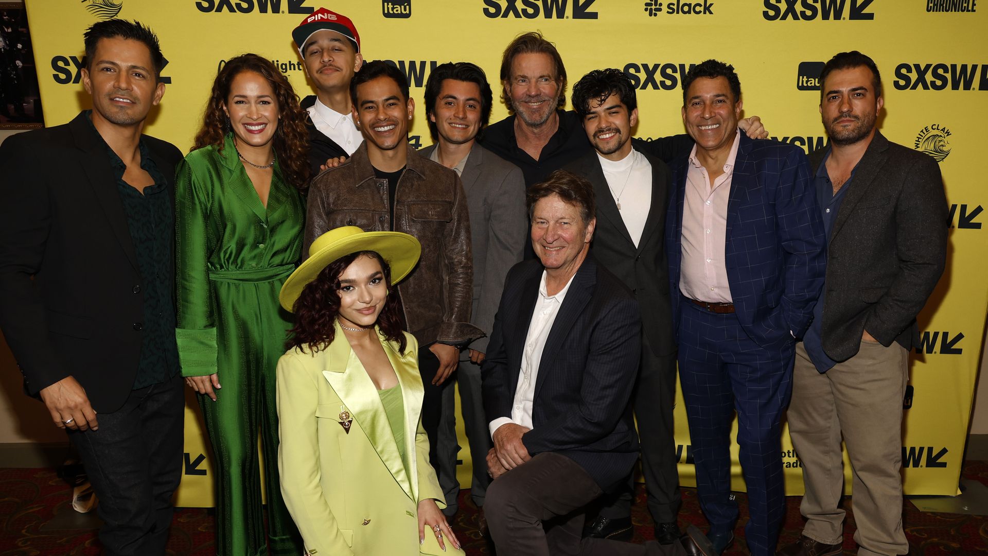 A group of people stand in front of a yellow banner with SXSW logos.