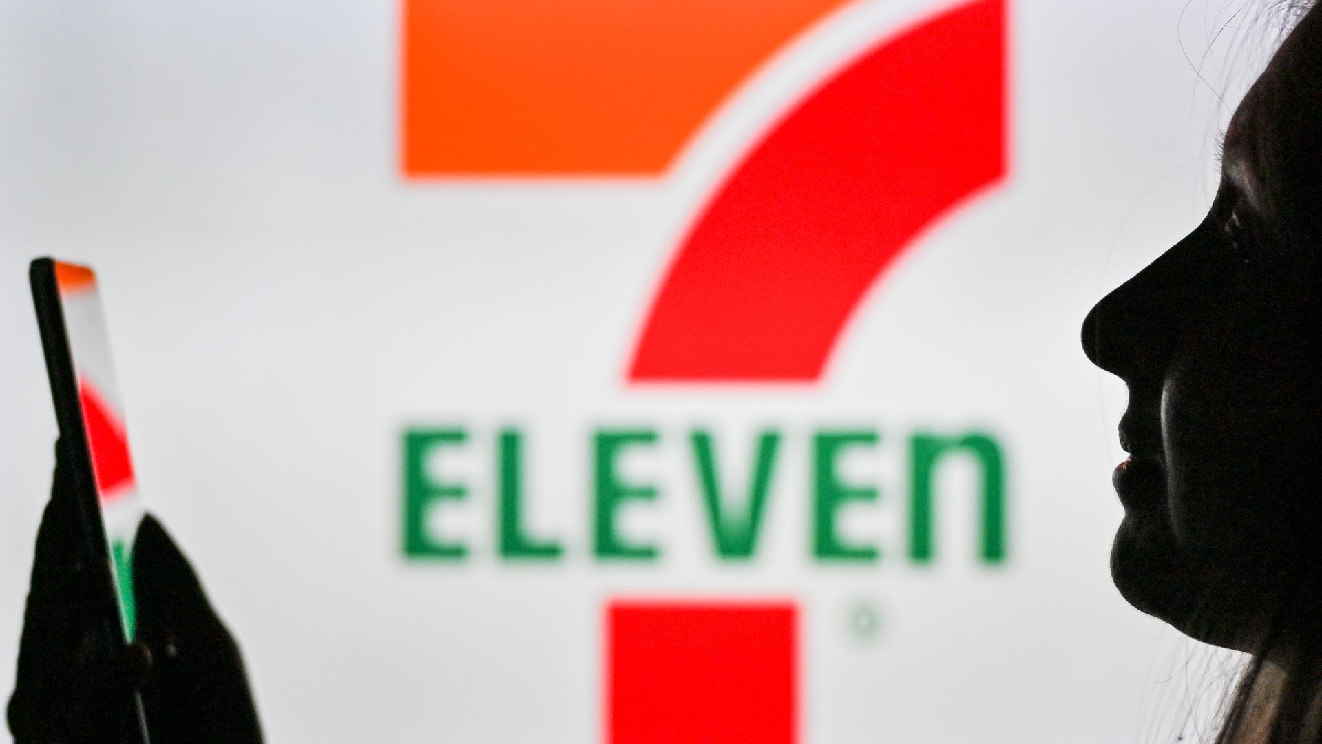 7-Eleven logo with woman holding phone 