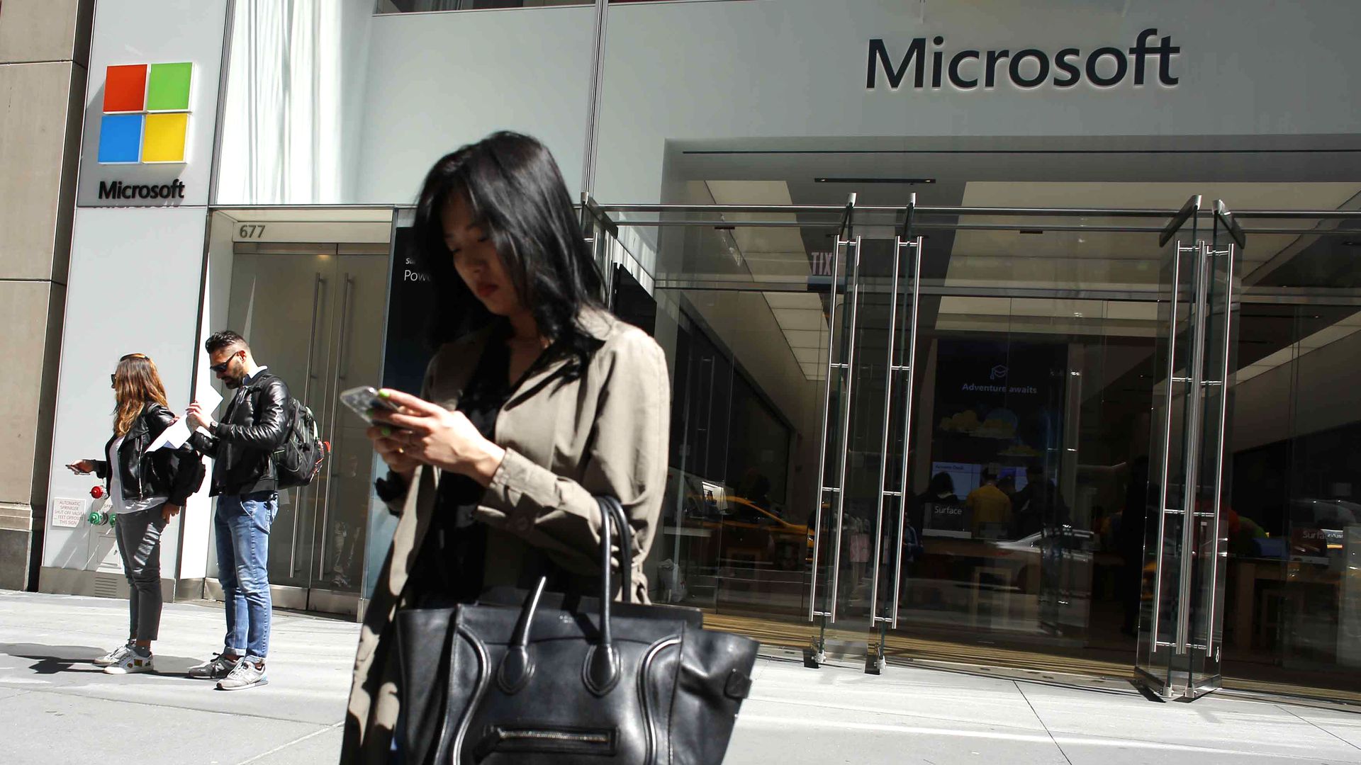 A photo of a woman on her phone outside a Microsoft office