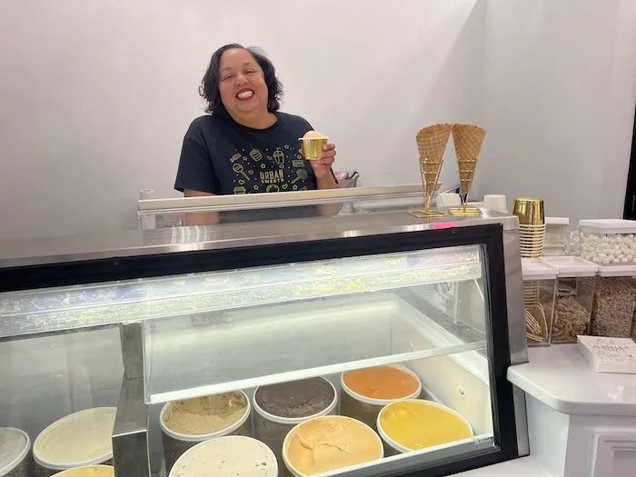 Woman holding ice cream behind a freezer