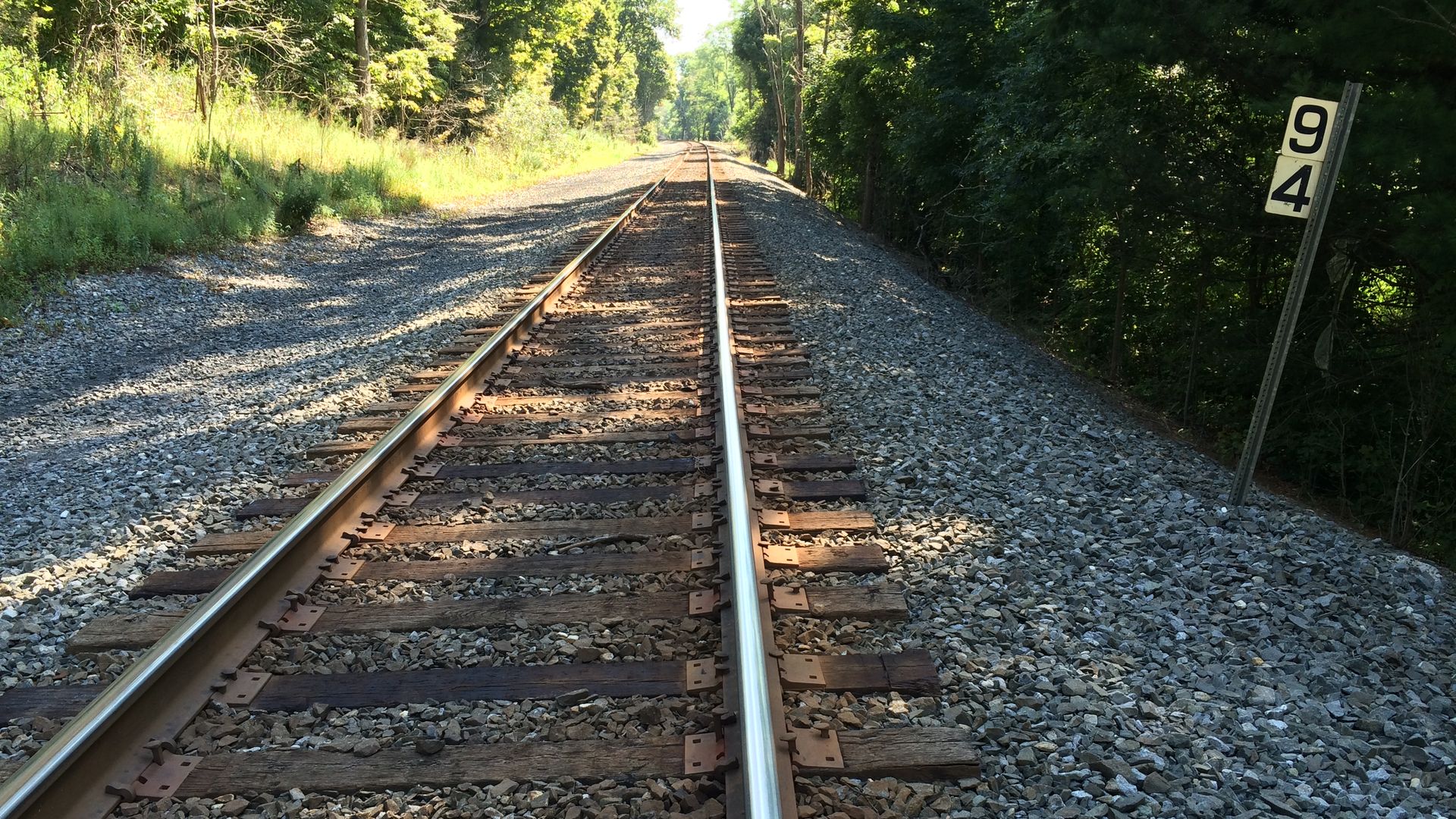 In this image, the camera points at train tracks.