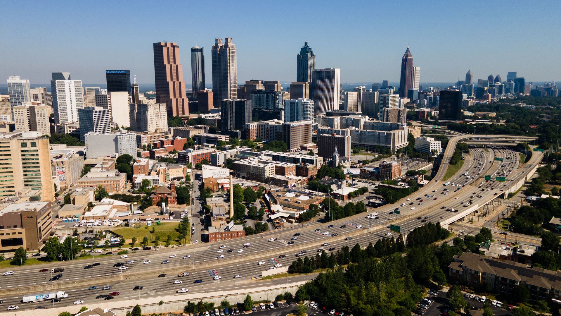 An aerial photograph of downtown Atlanta's skyscrapers with the interstate in the foreground and Buckhead in the background