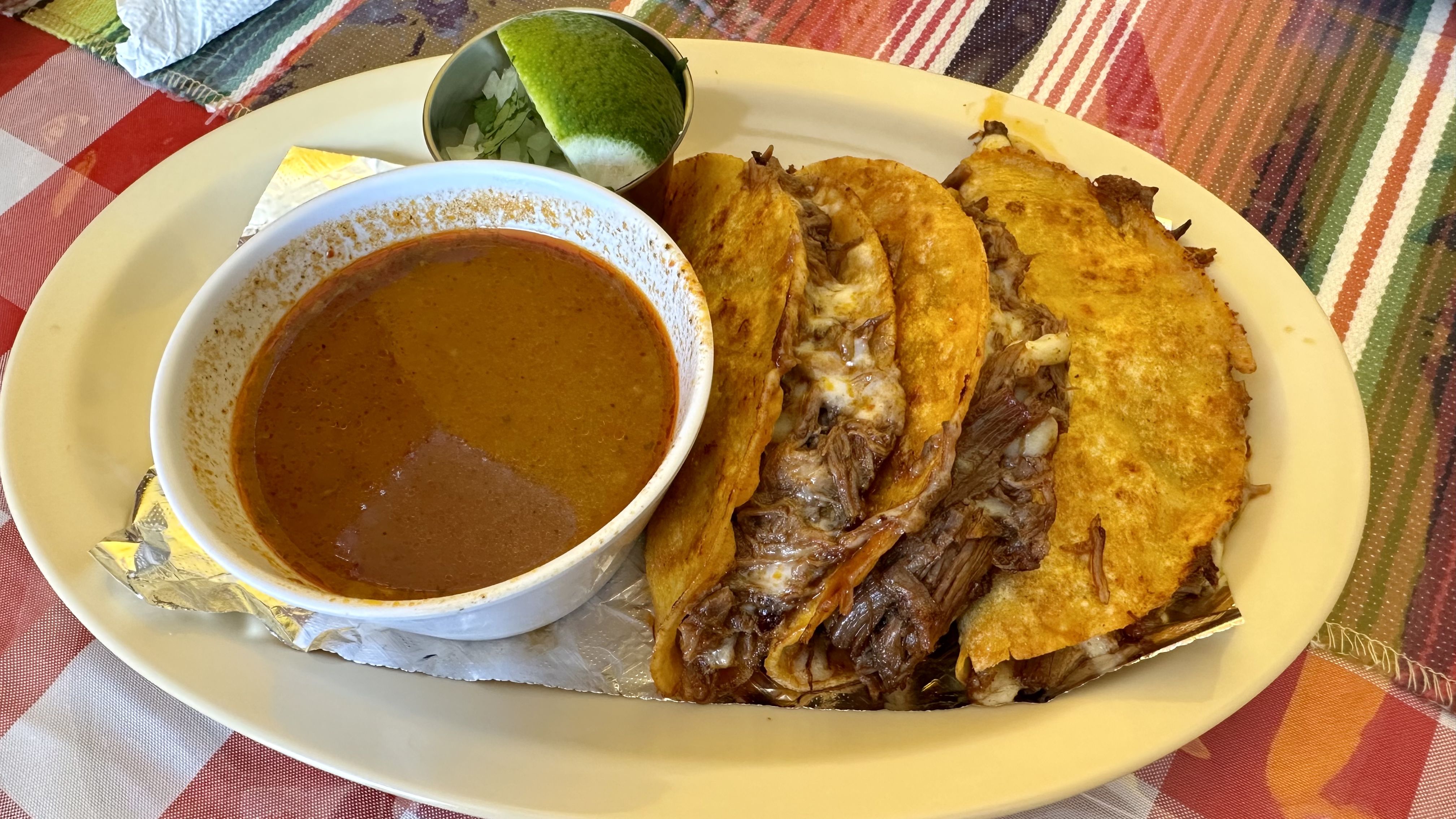 Photo shows a plate of birria tacos.