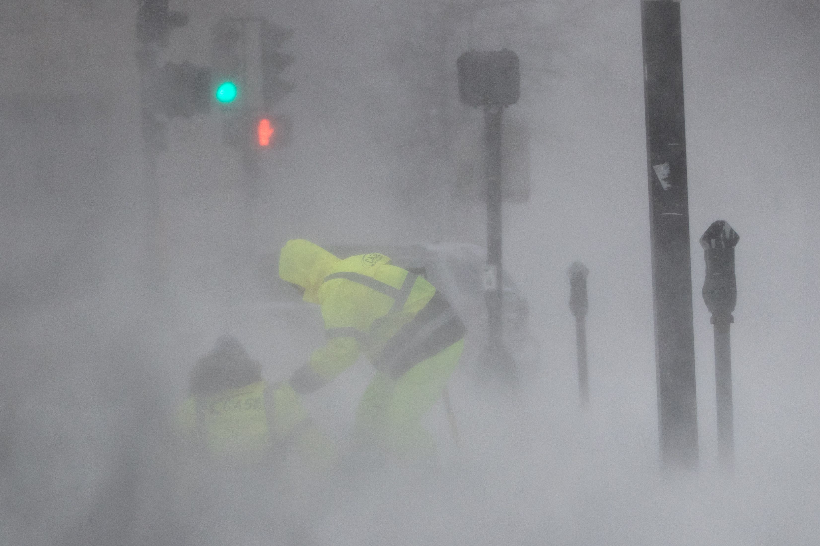 A worker helps another who was blown down by wind as Winter Storm Kenan bears down on January 29, 2022 in Boston, Massachusetts.