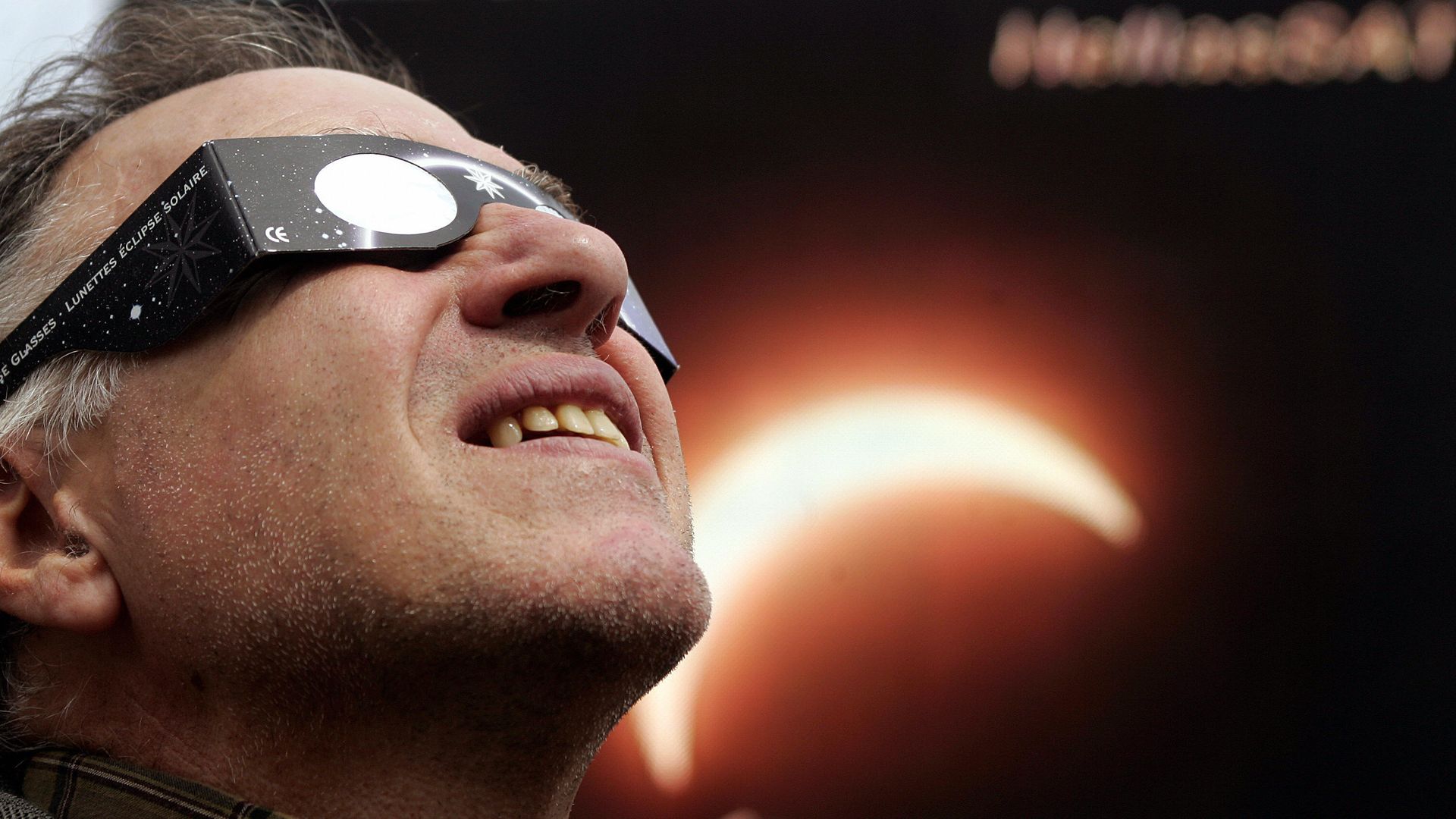 A man looks into the sky with eclipse sunglasses on.
