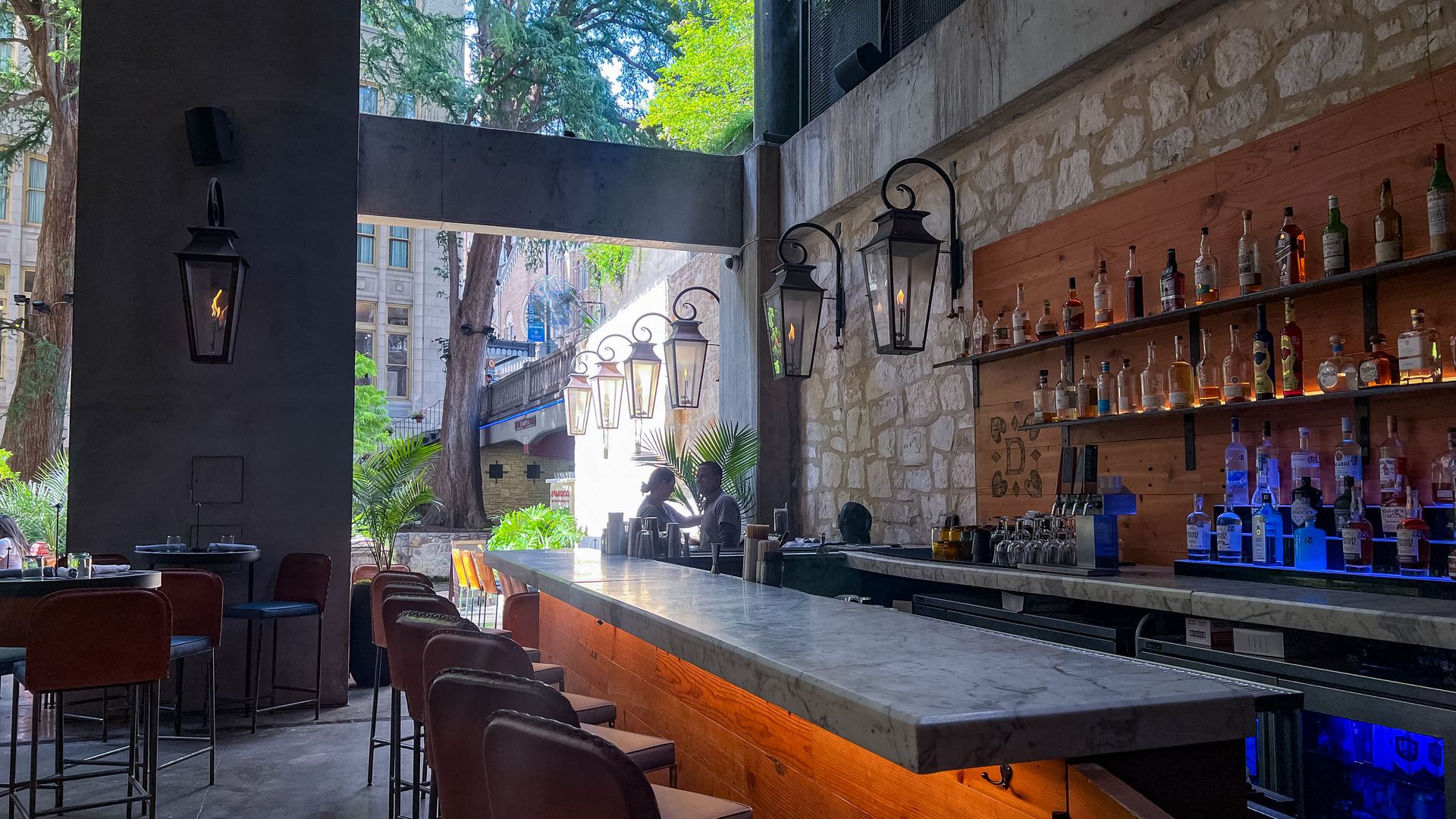 Bar view of a half outside, half inside space accented with rows of lamps.