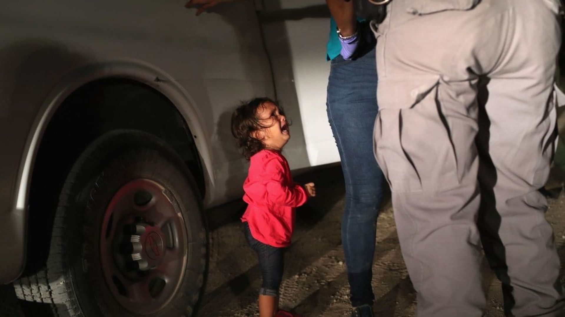 A girl crying as her mother is searched by a border patrol agent