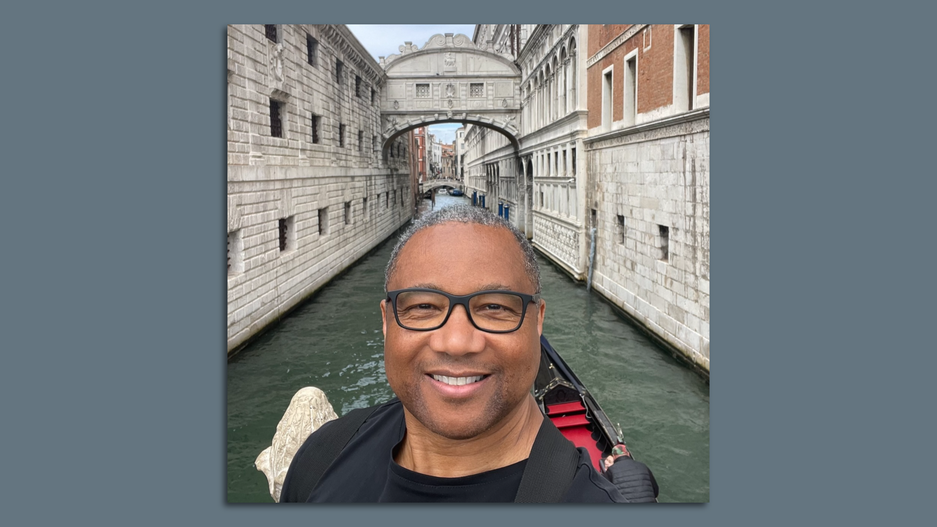 A man in glasses on a gondola in Venice, Italy.