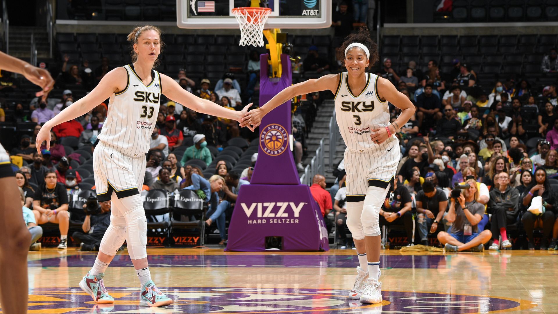 Photo of two women high-fiving during basketball game. 